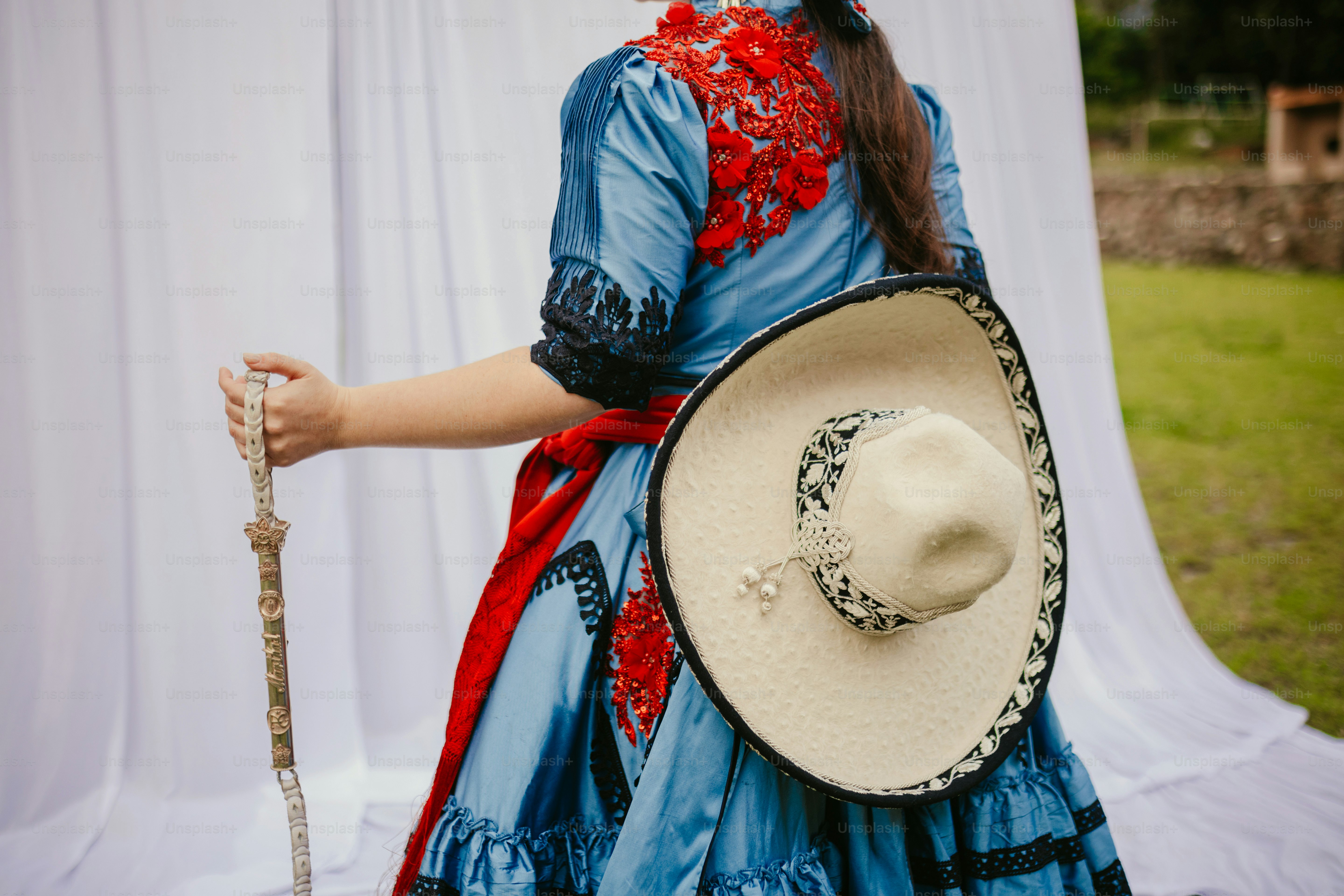 Woman in a blue dress with red embroidery and hat.