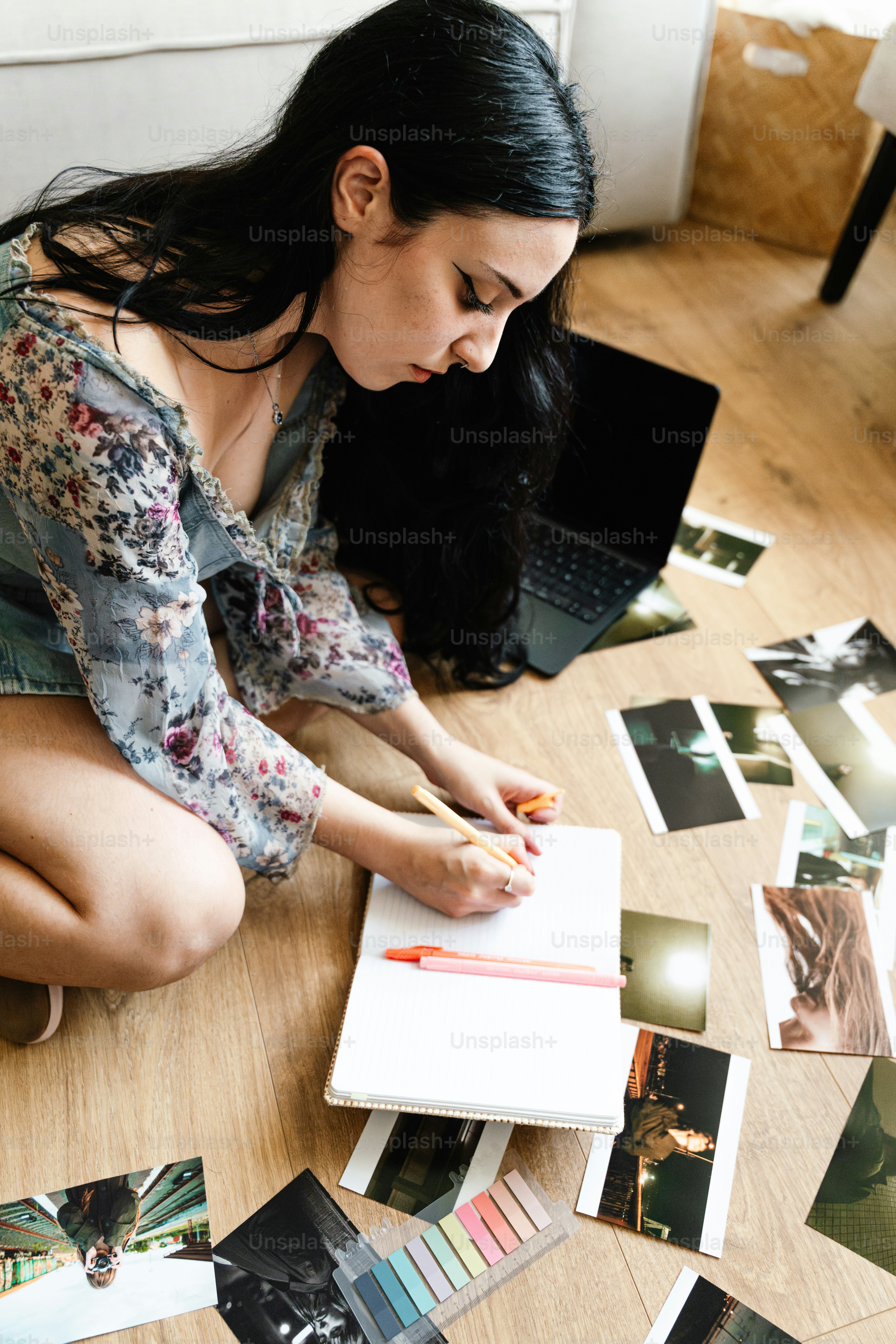 Woman writing in notebook surrounded by scattered photos