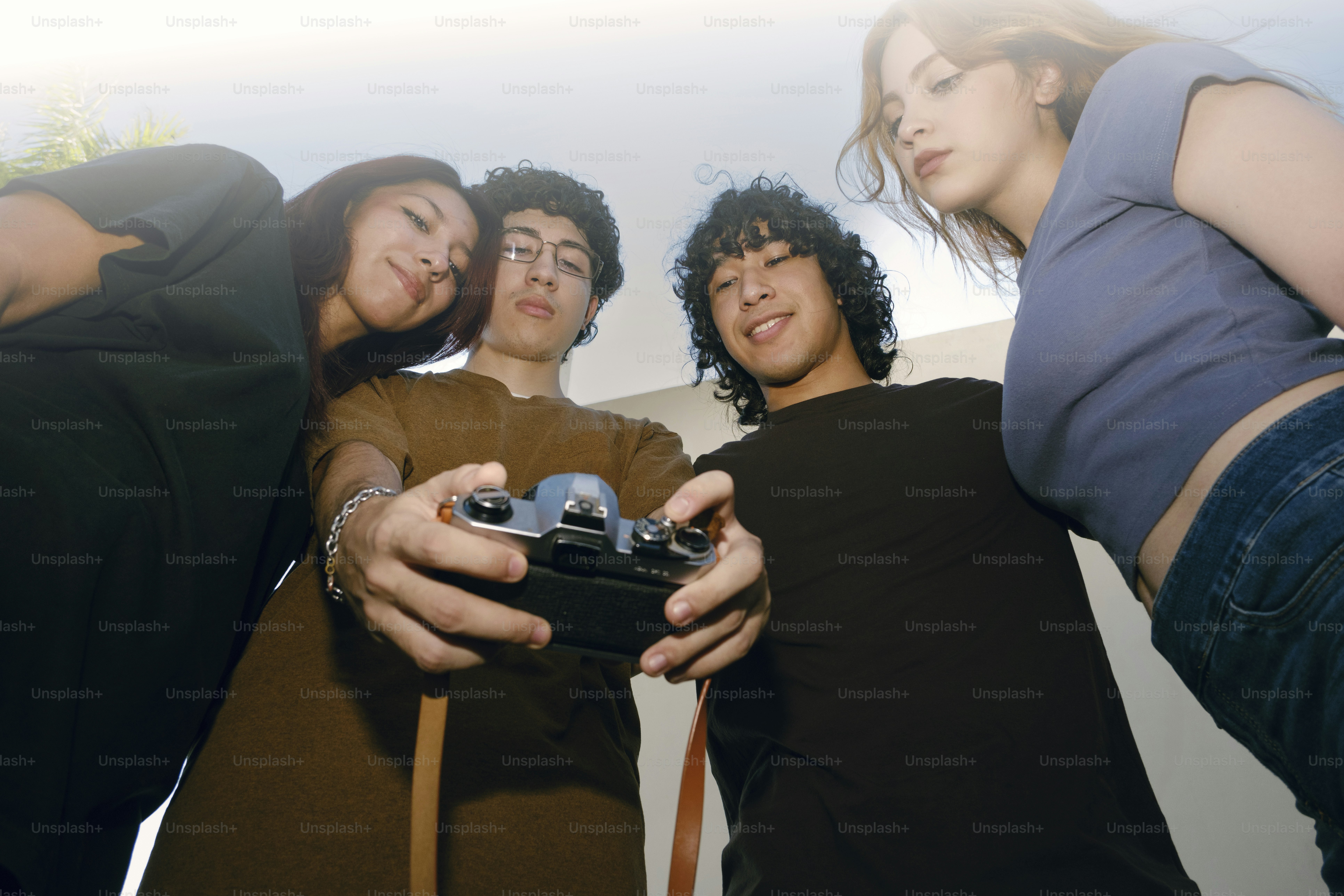 Four friends looking down at a camera