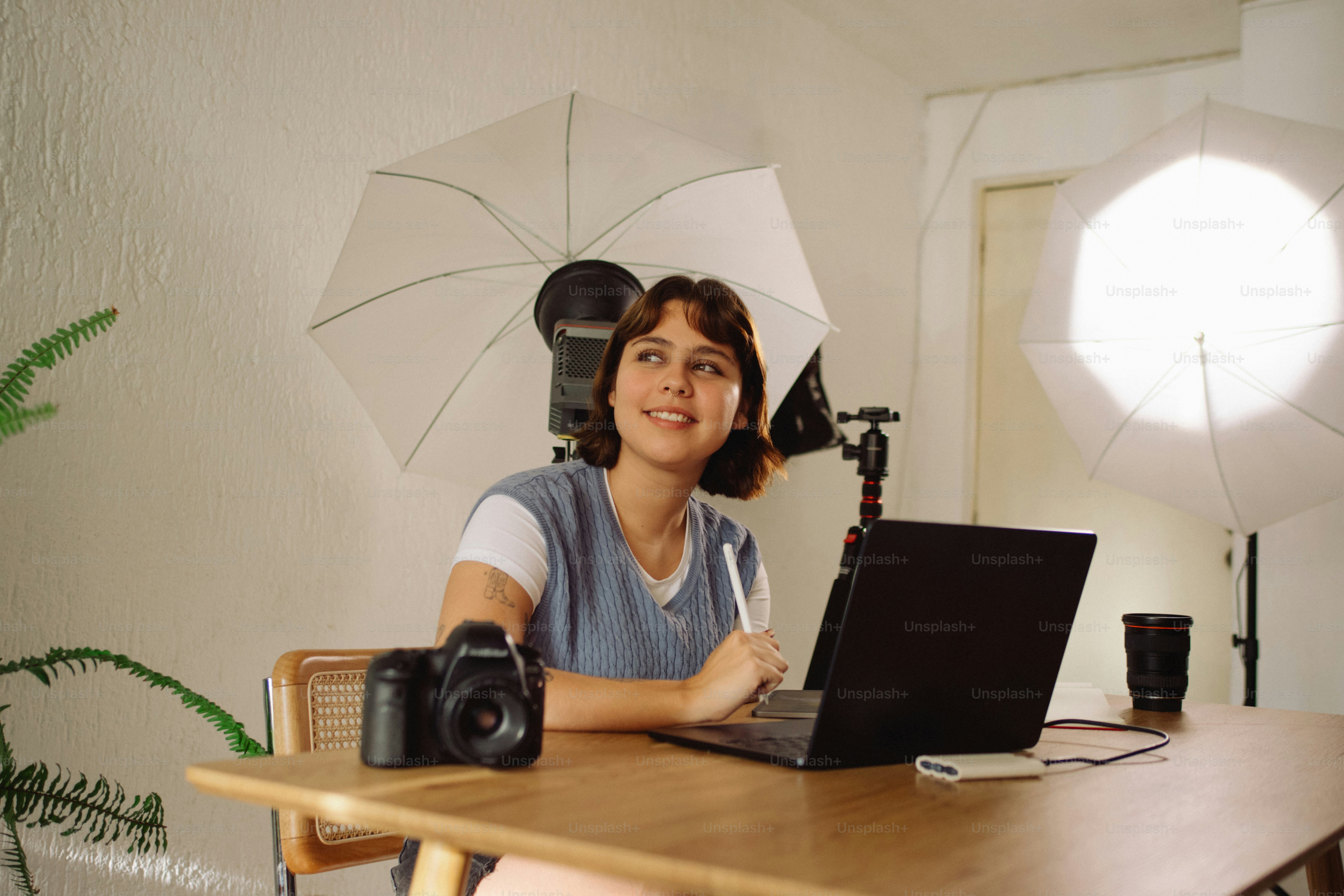 Young woman working on laptop with camera and lights