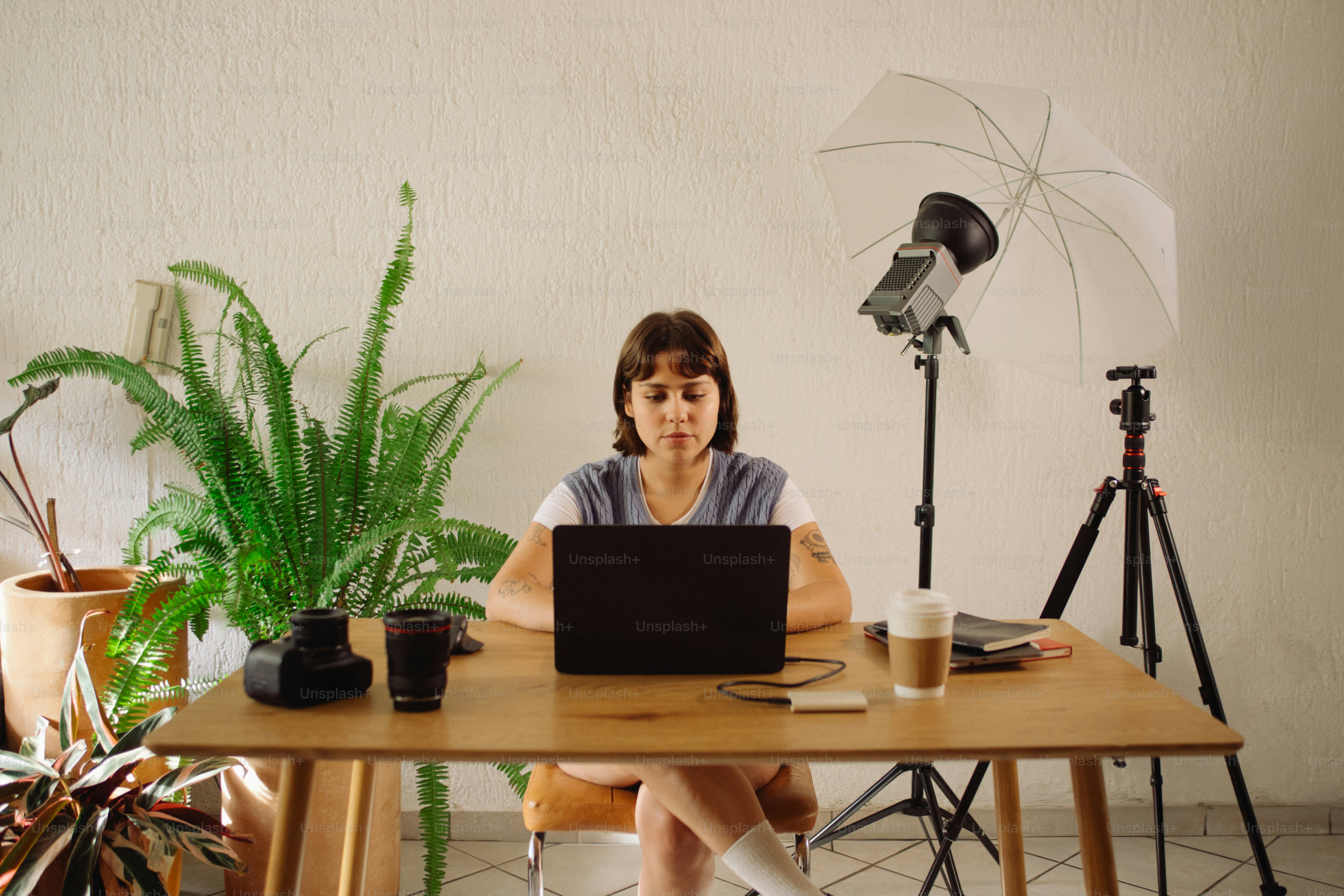 Woman working on laptop at desk with camera and light.