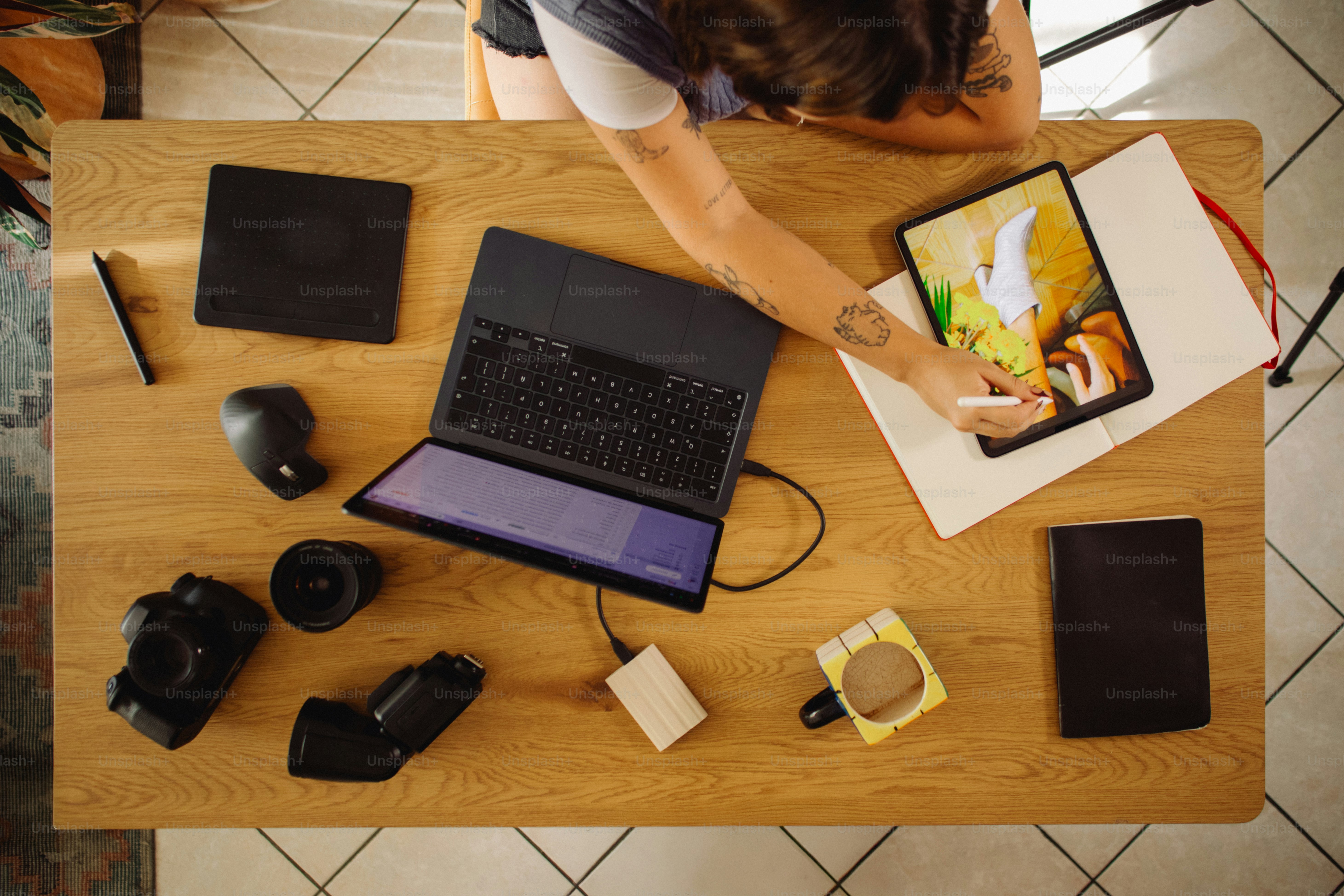 Person drawing on tablet next to laptop and camera.