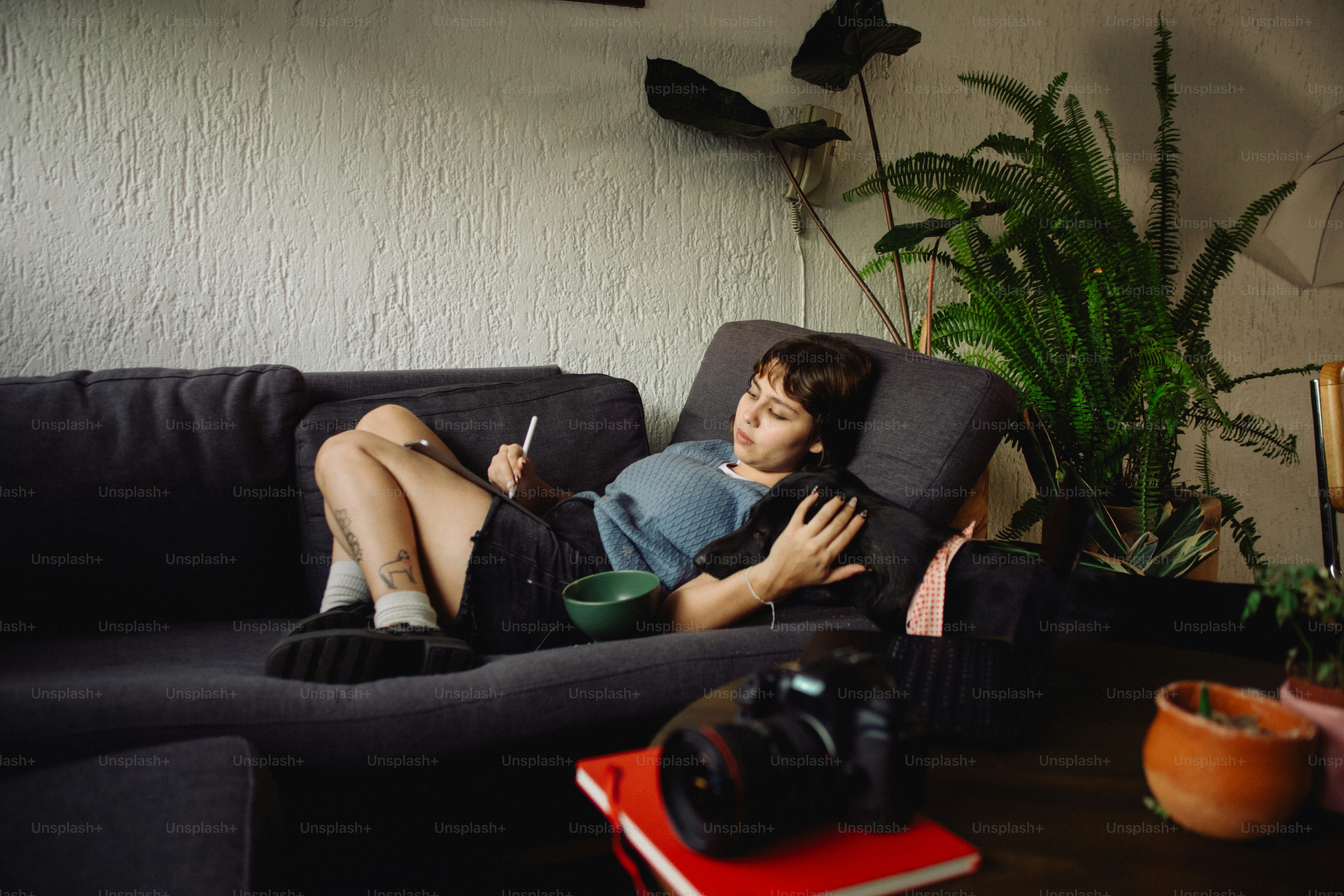Person relaxing on couch with phone and bowl.