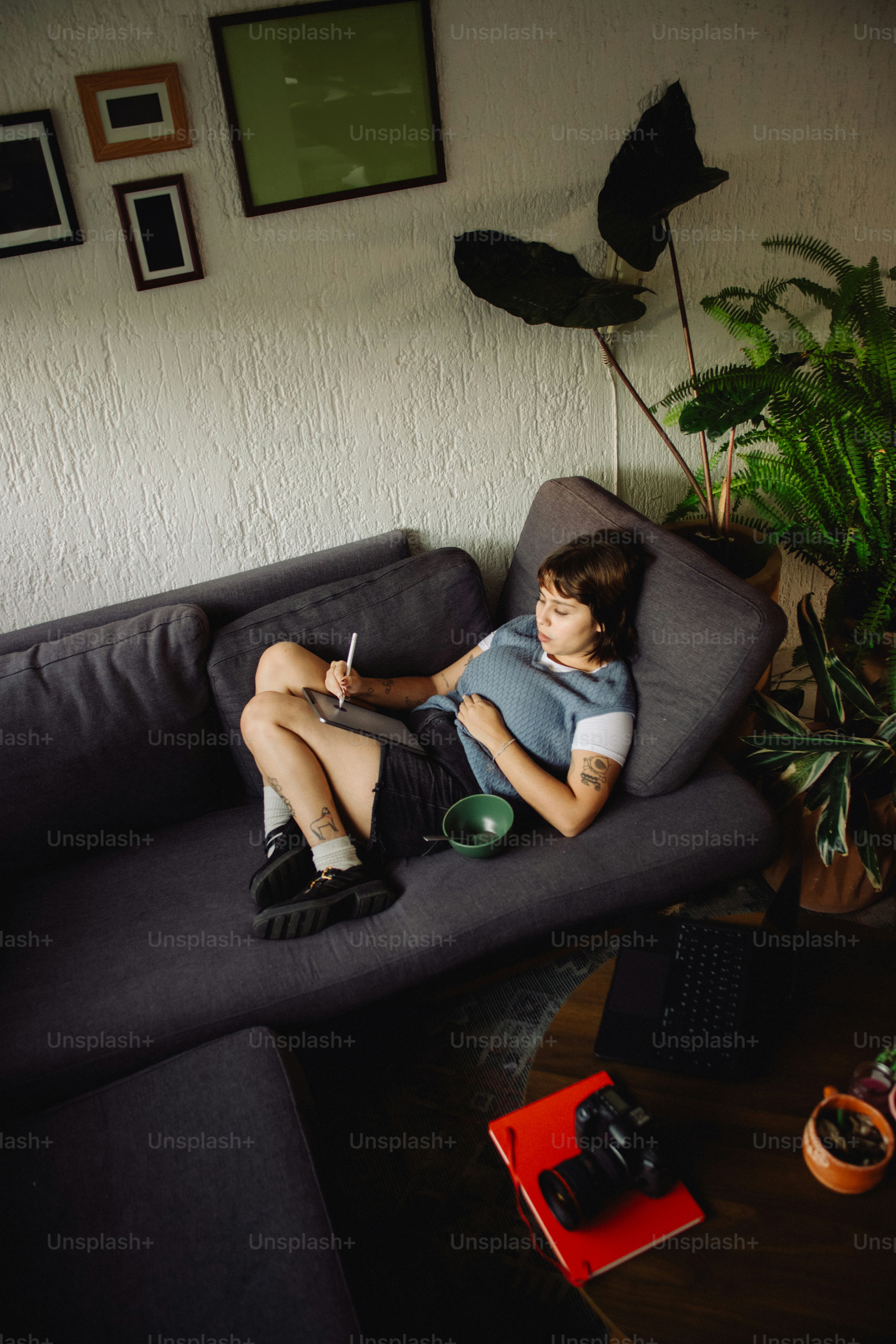 Person drawing on tablet while relaxing on sofa.