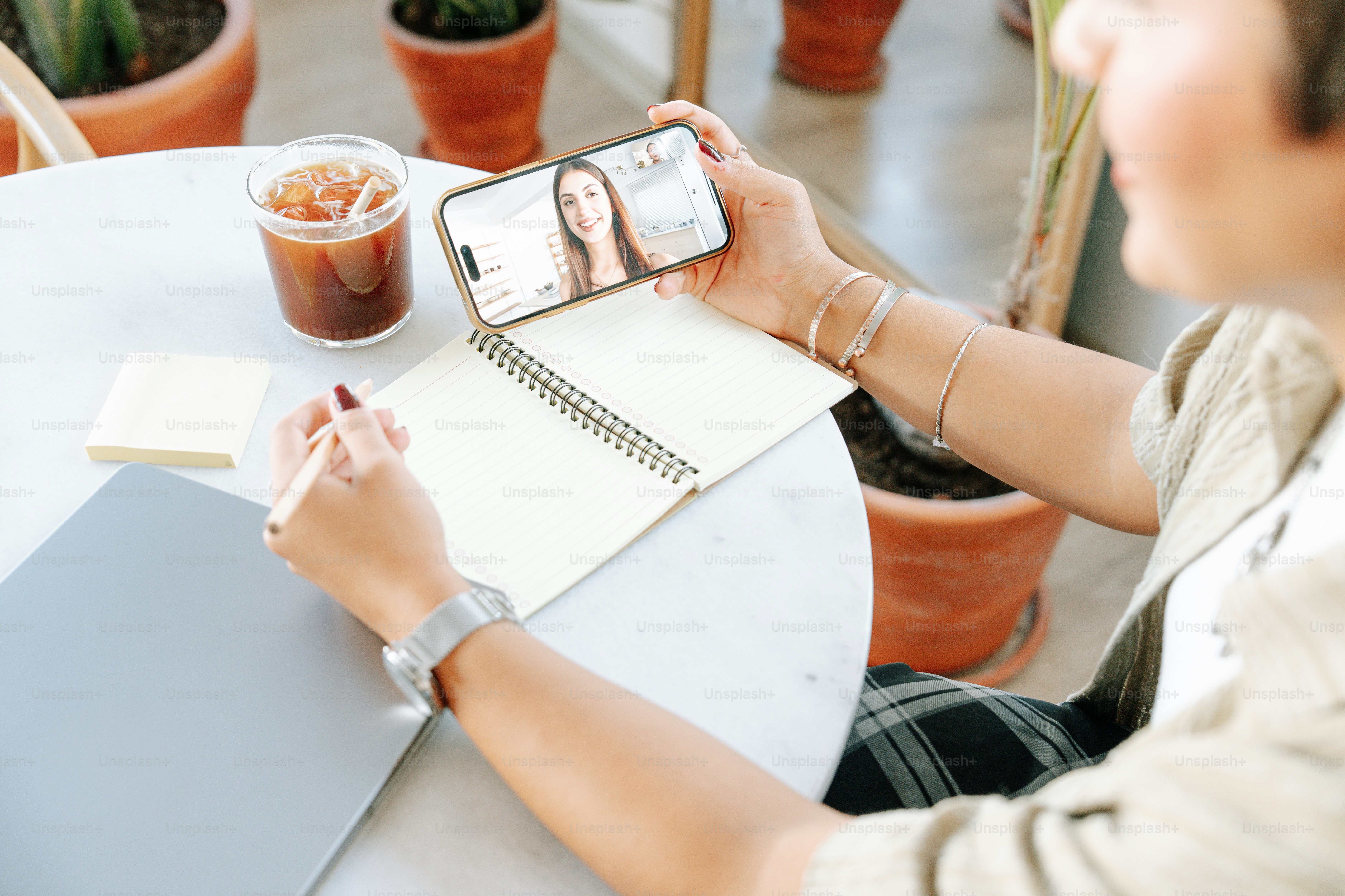 Woman video calling while taking notes at table