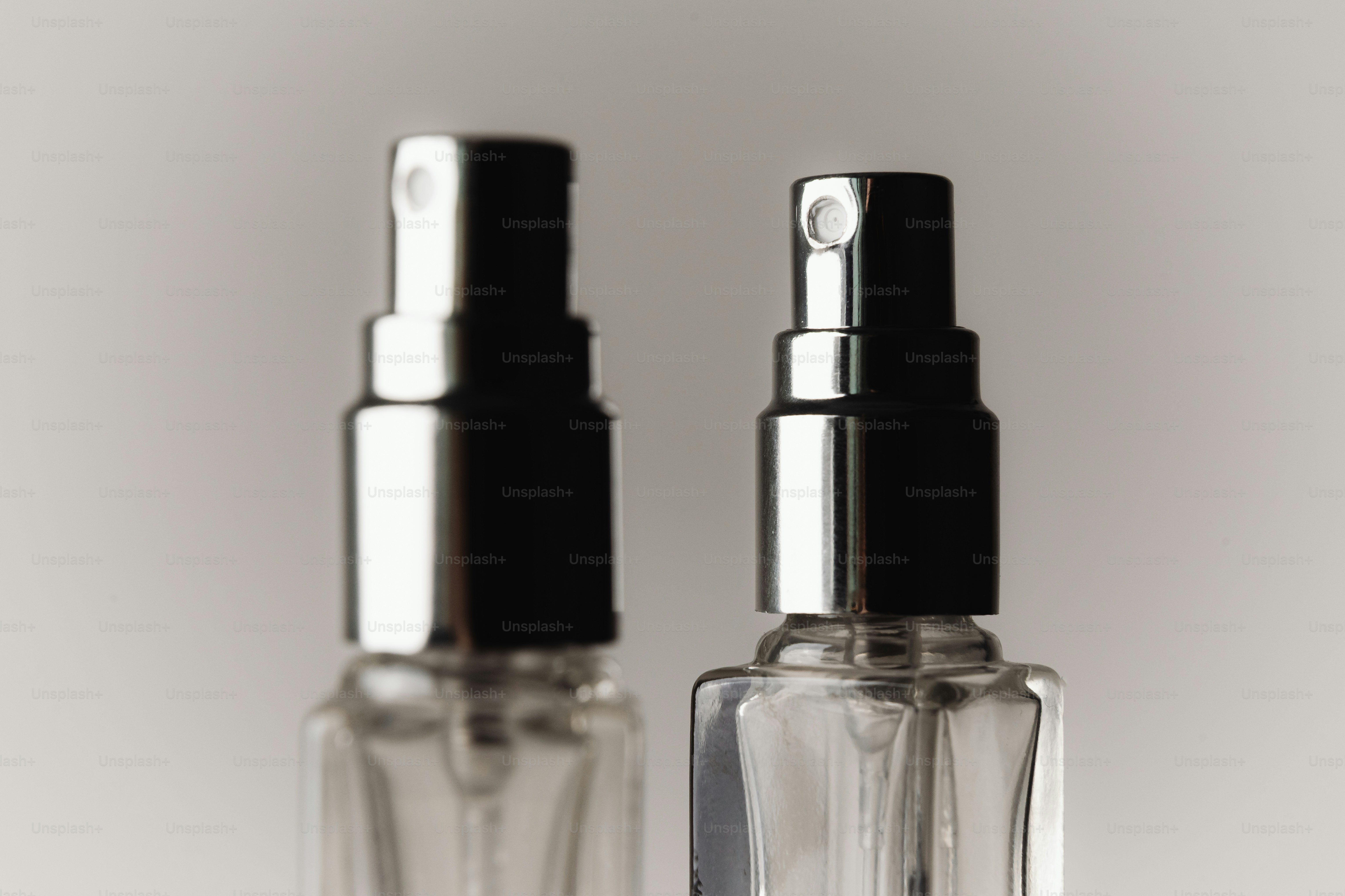 Two clear spray bottles with silver and black caps