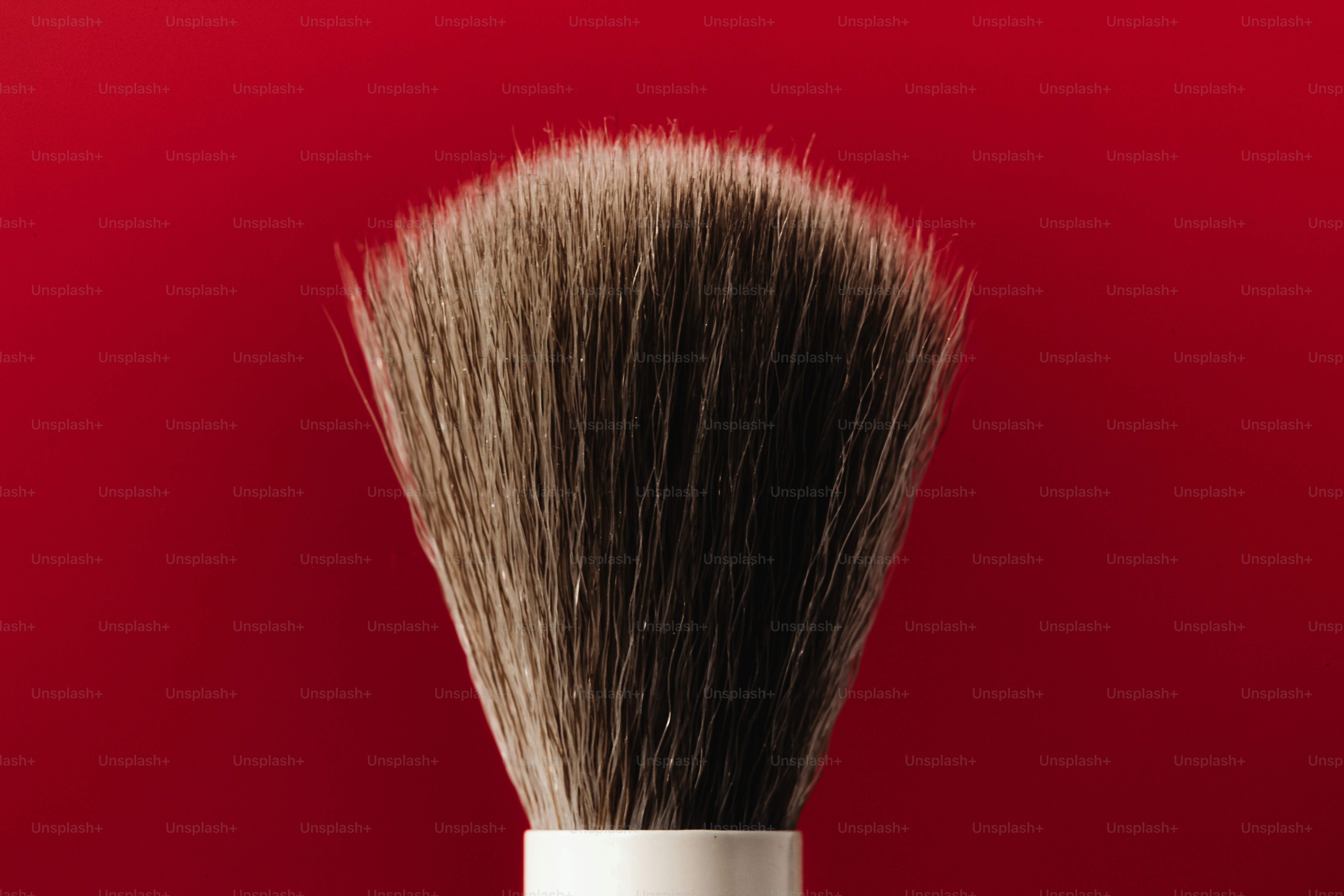 Gros plan d’un pinceau de maquillage sur fond rouge