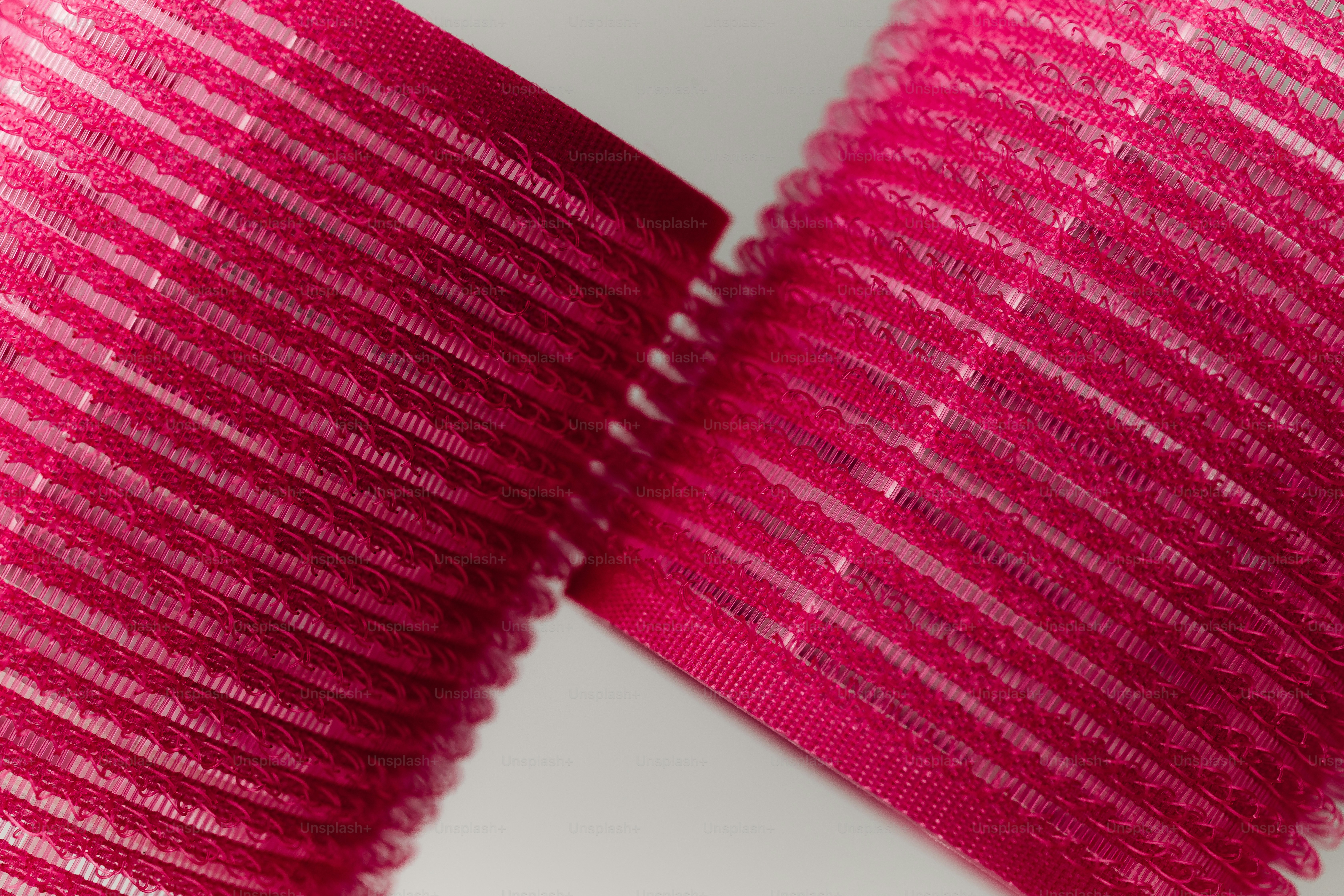 Two pink velcro rollers against a white background.