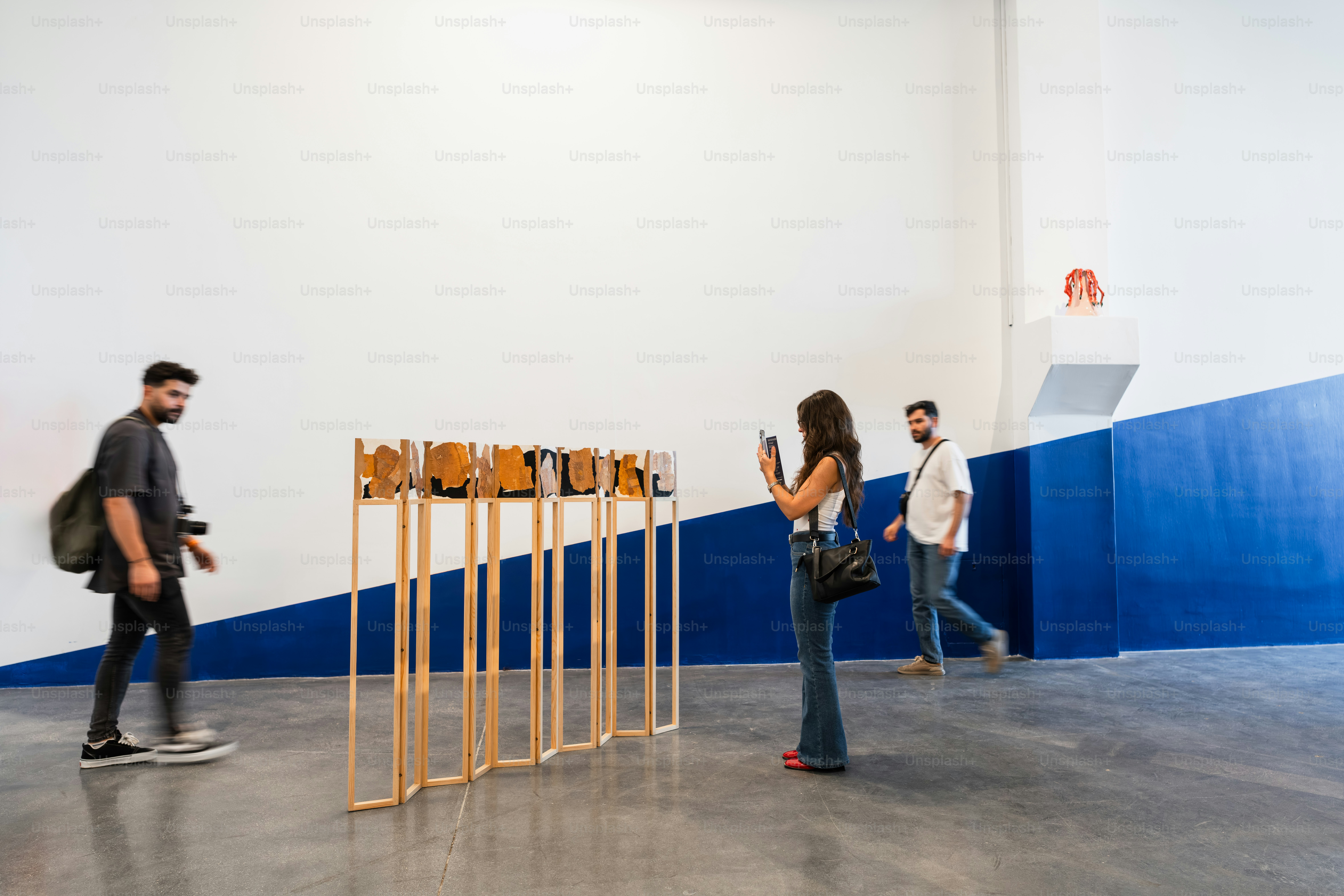 People observe artwork in a modern gallery space.