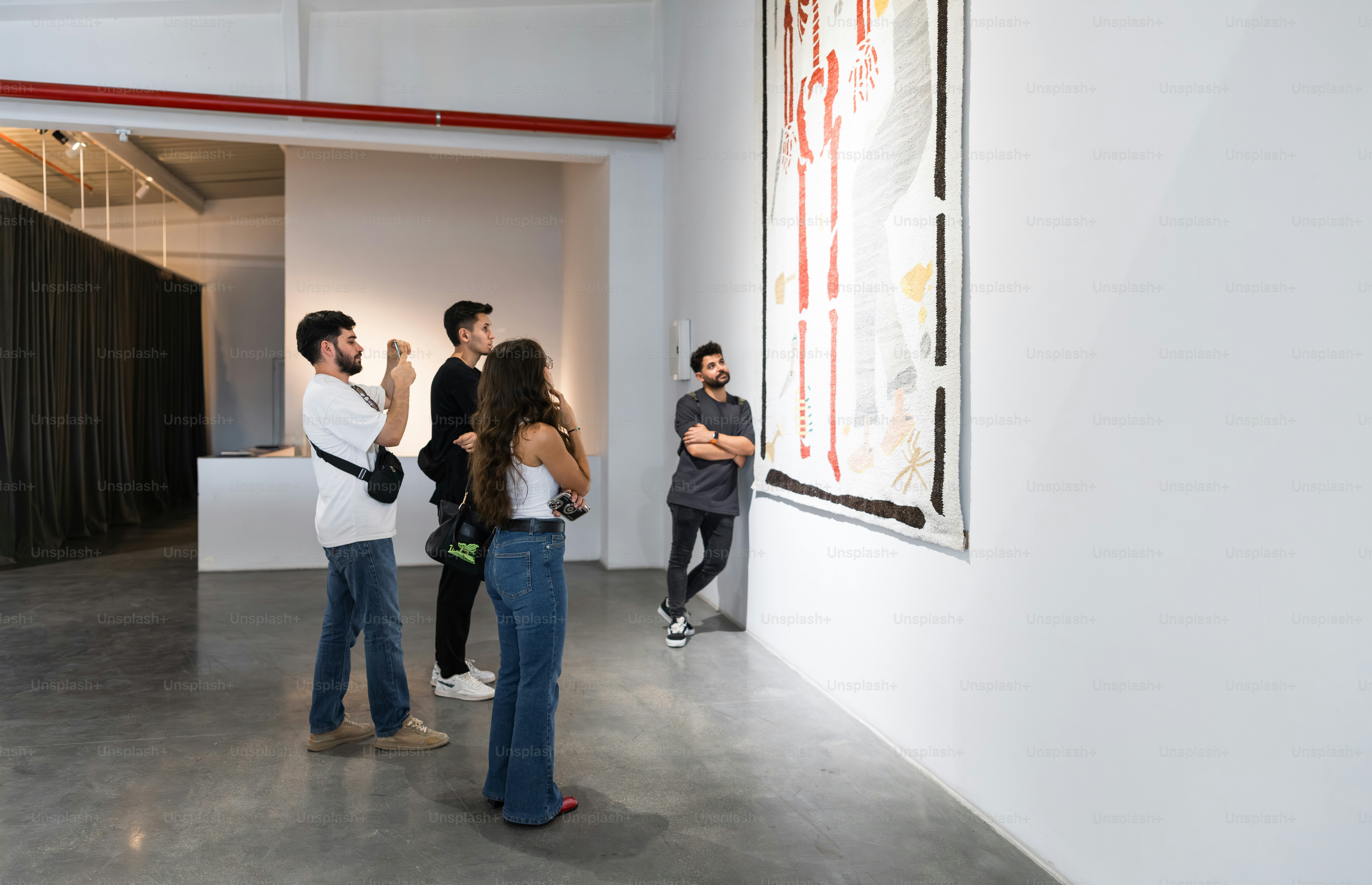 People observe large artwork in a modern gallery.