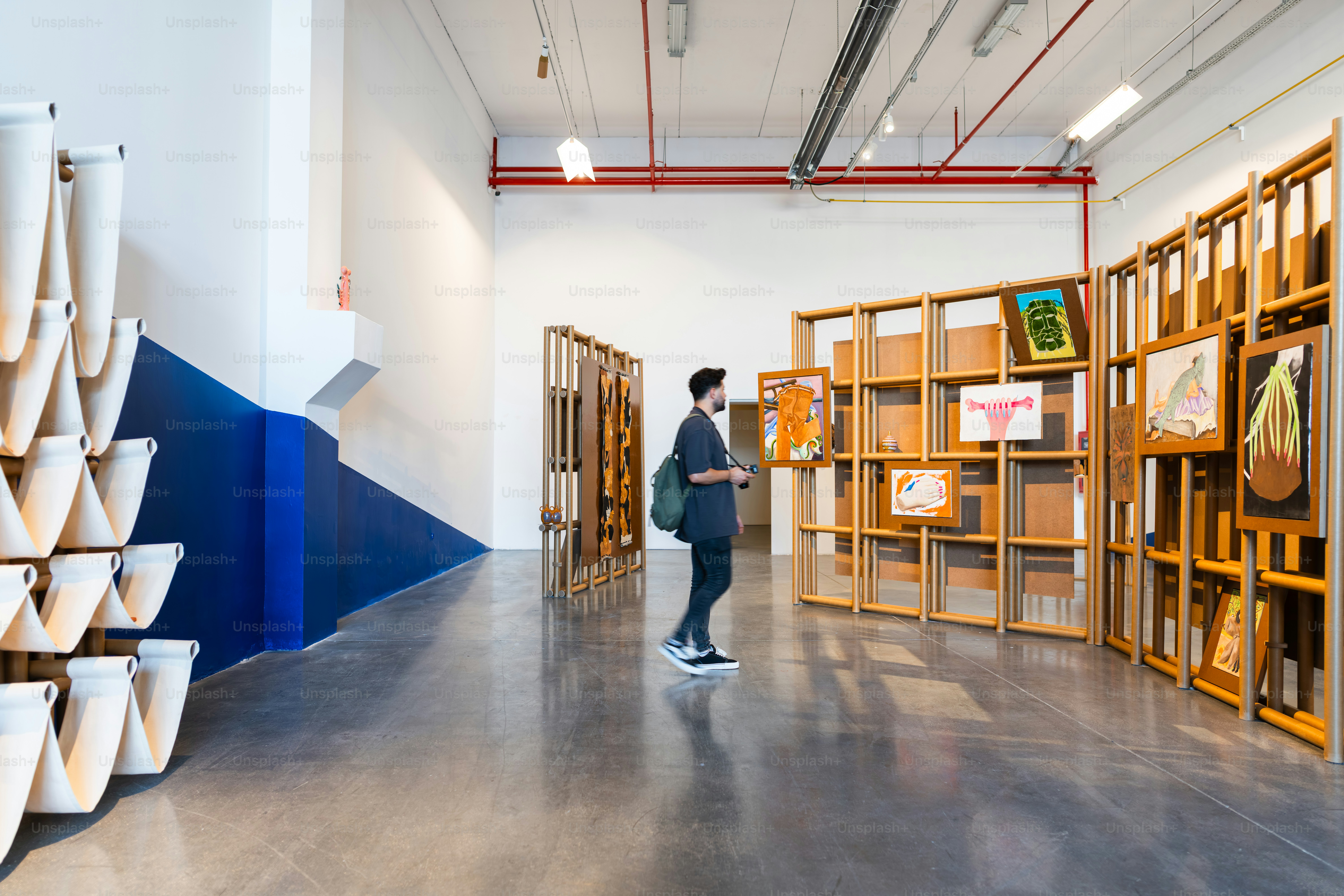 Homem observando exposição de arte com molduras de madeira.