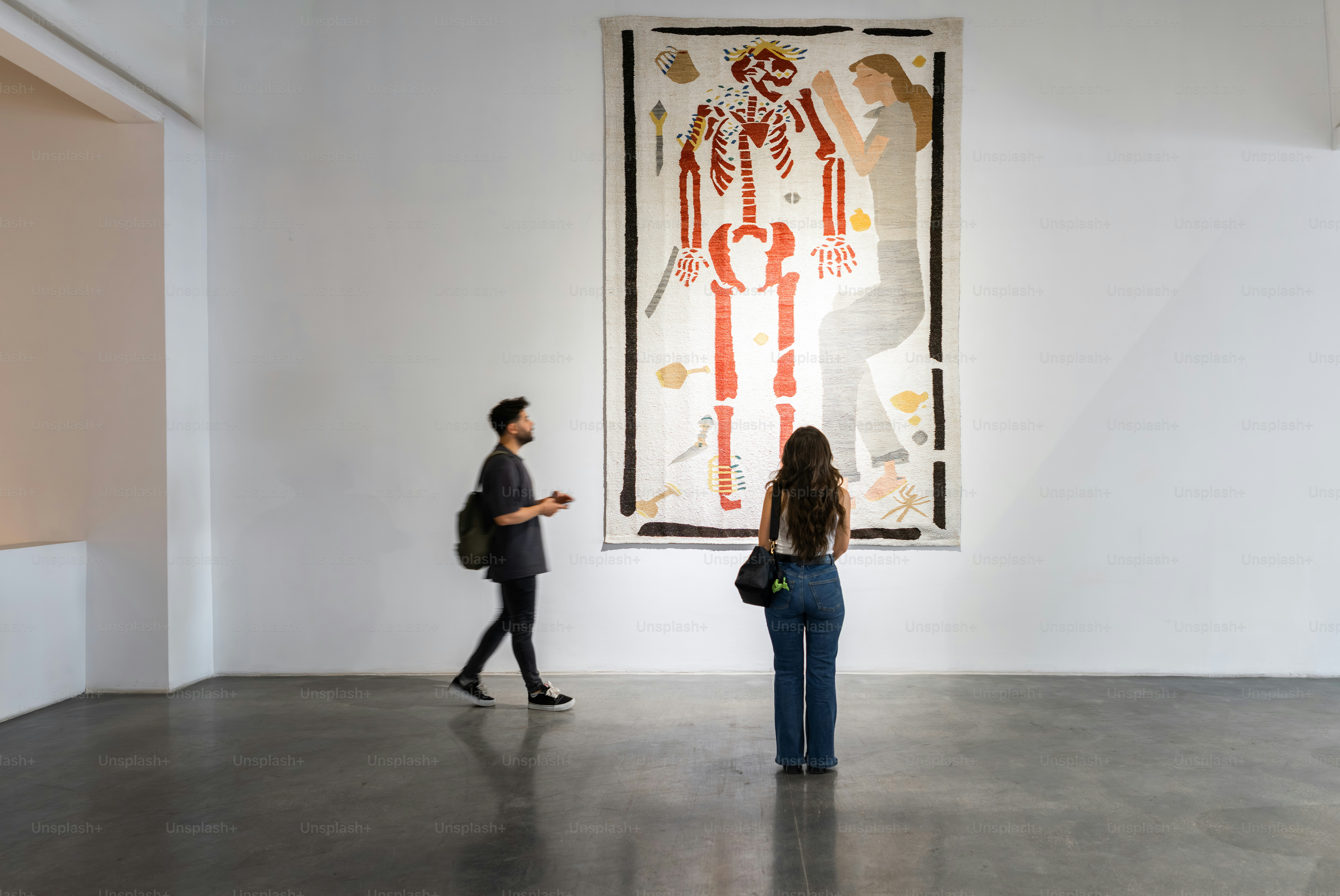 Two people observe large artwork in a gallery