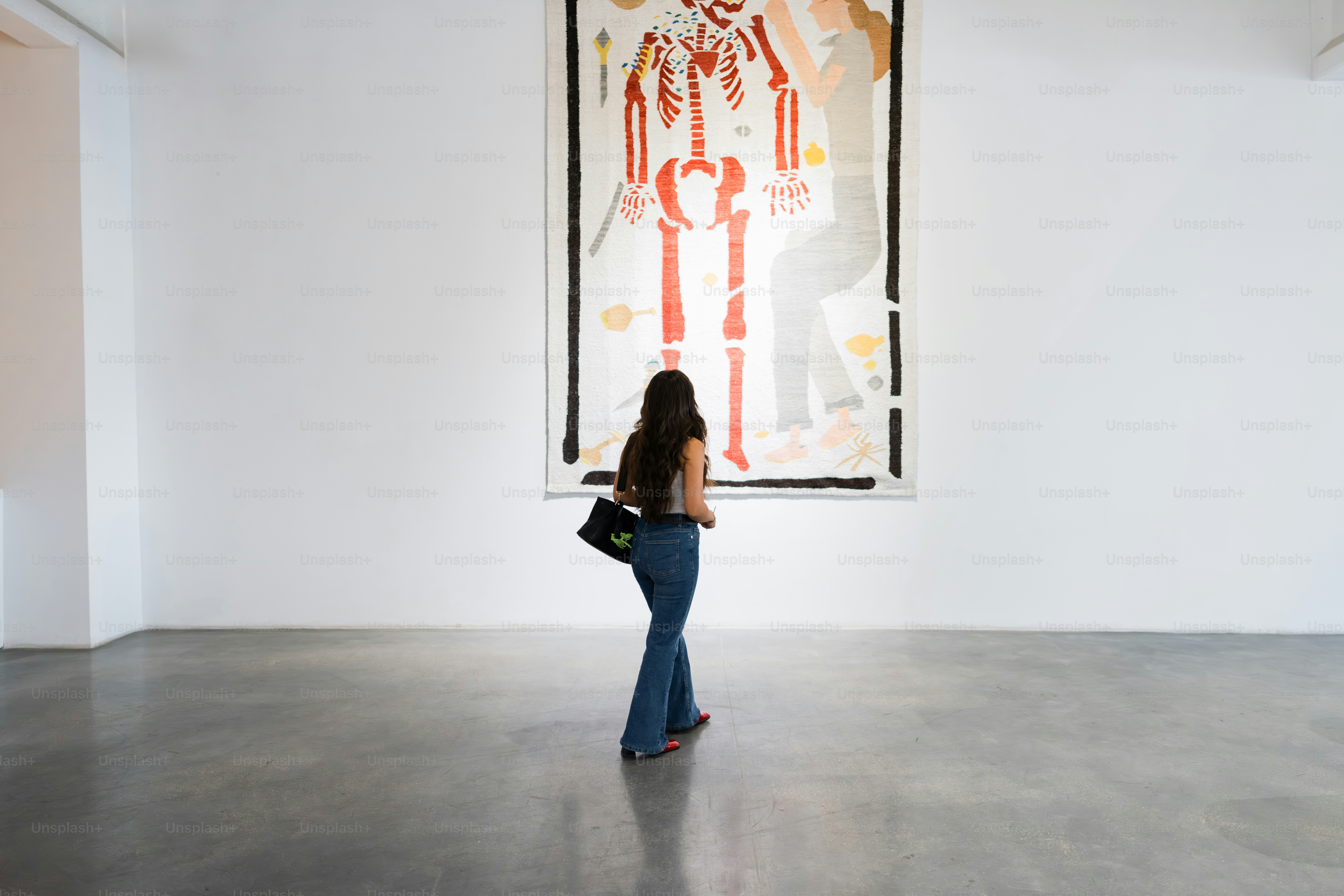 Woman observing large artwork in a white gallery.