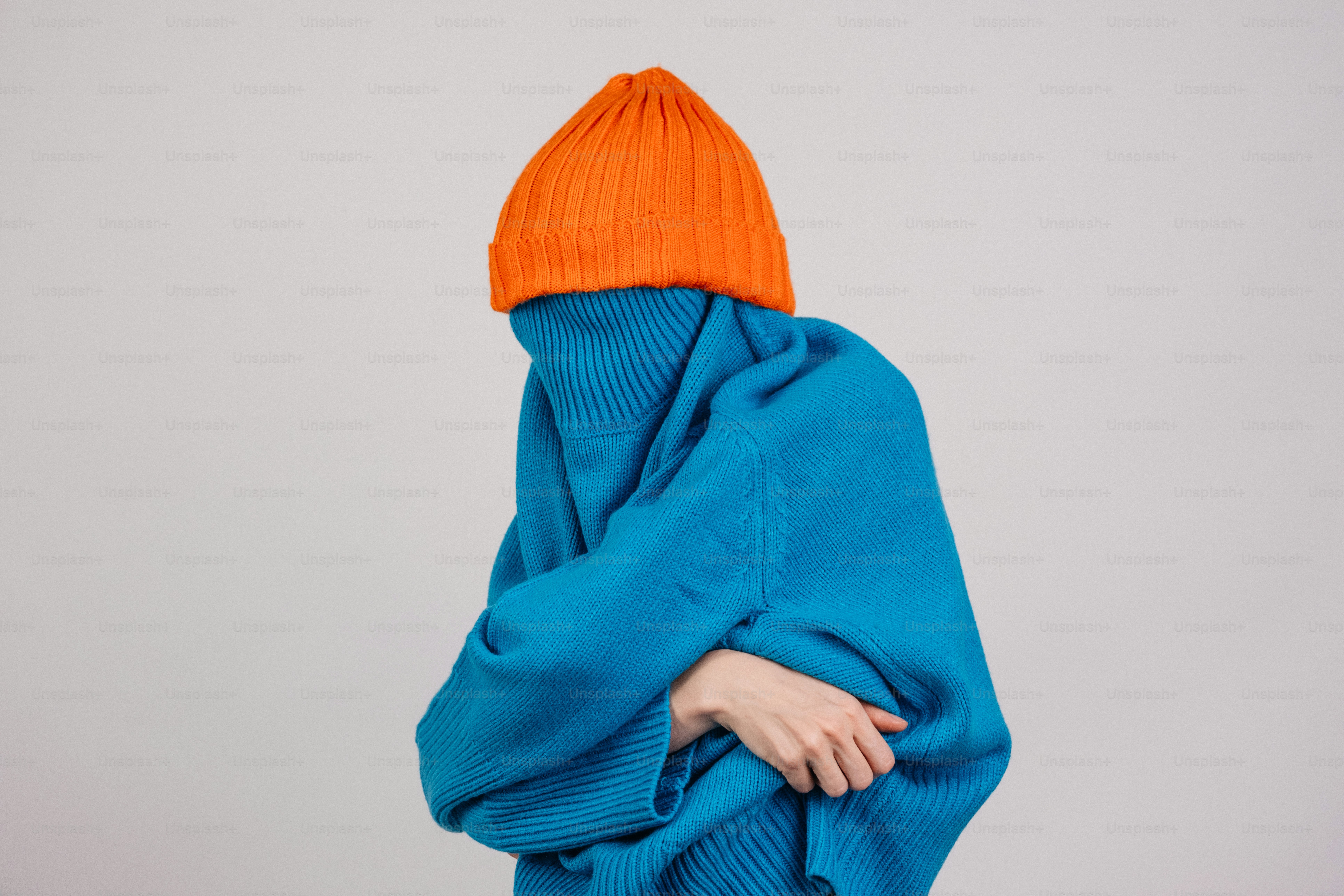 Person wrapped in blue blanket wearing orange hat