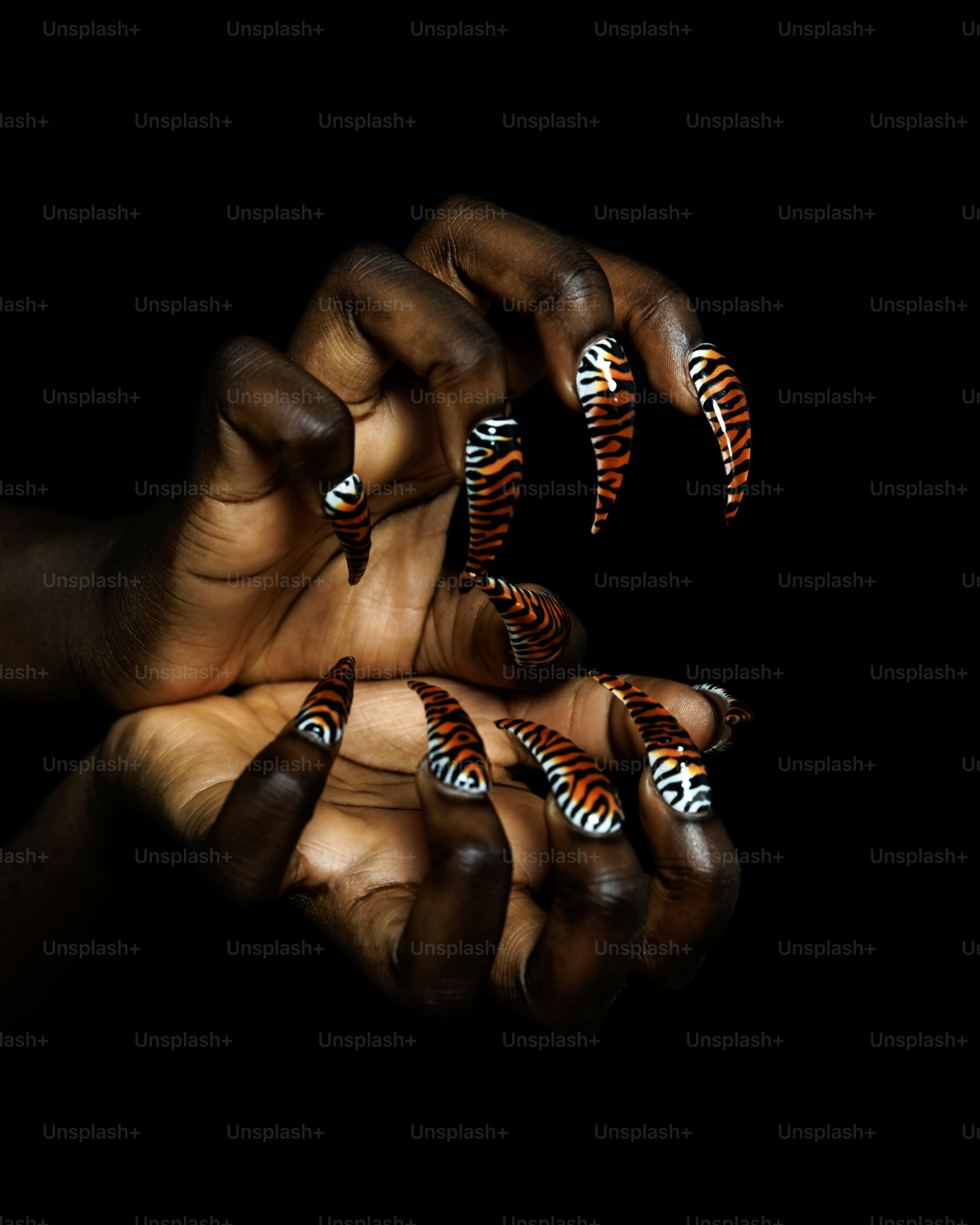 Mains avec de longs ongles en acrylique à rayures tigrées