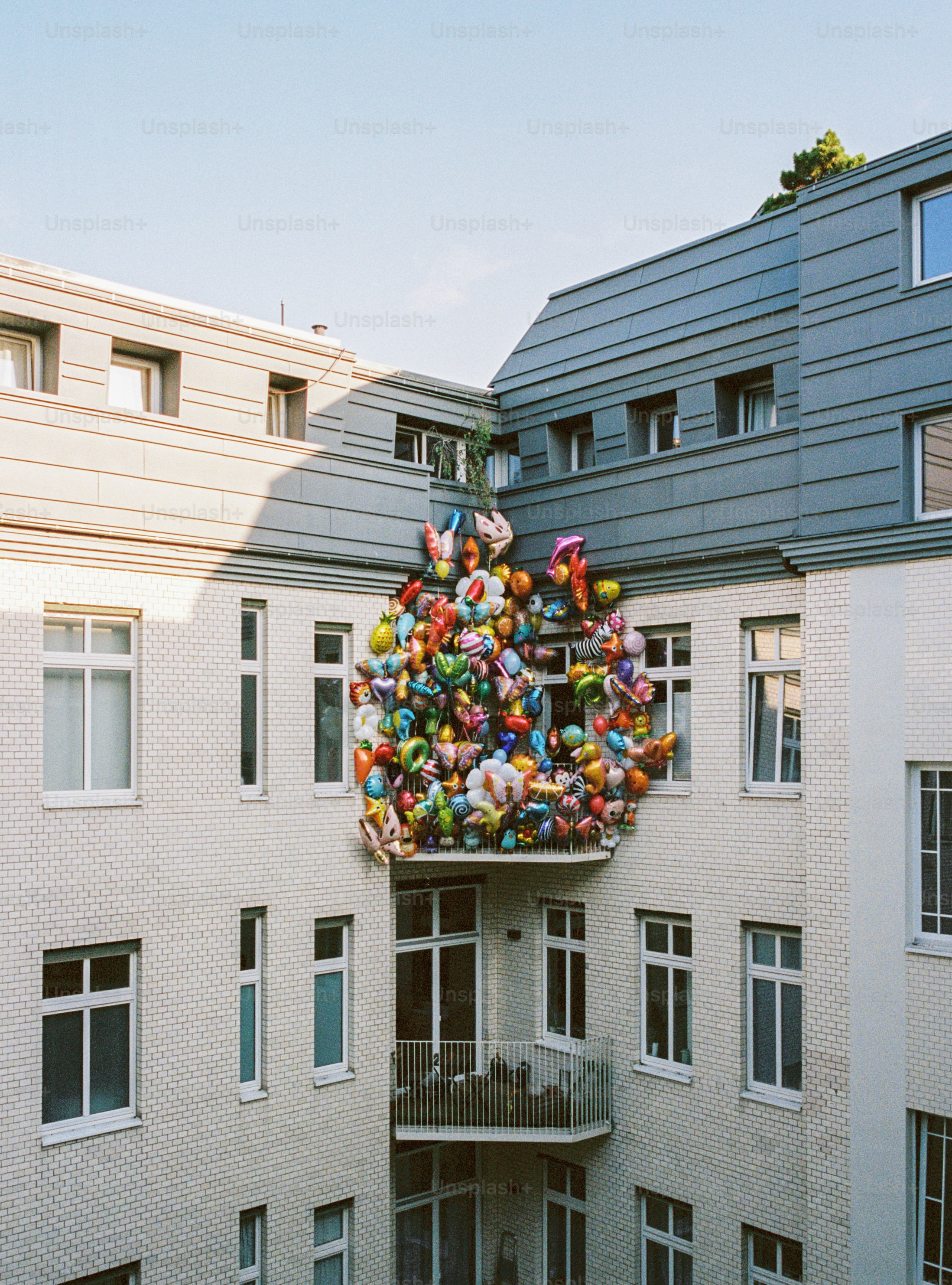 Un grand groupe de ballons colorés sur la façade d’un bâtiment.