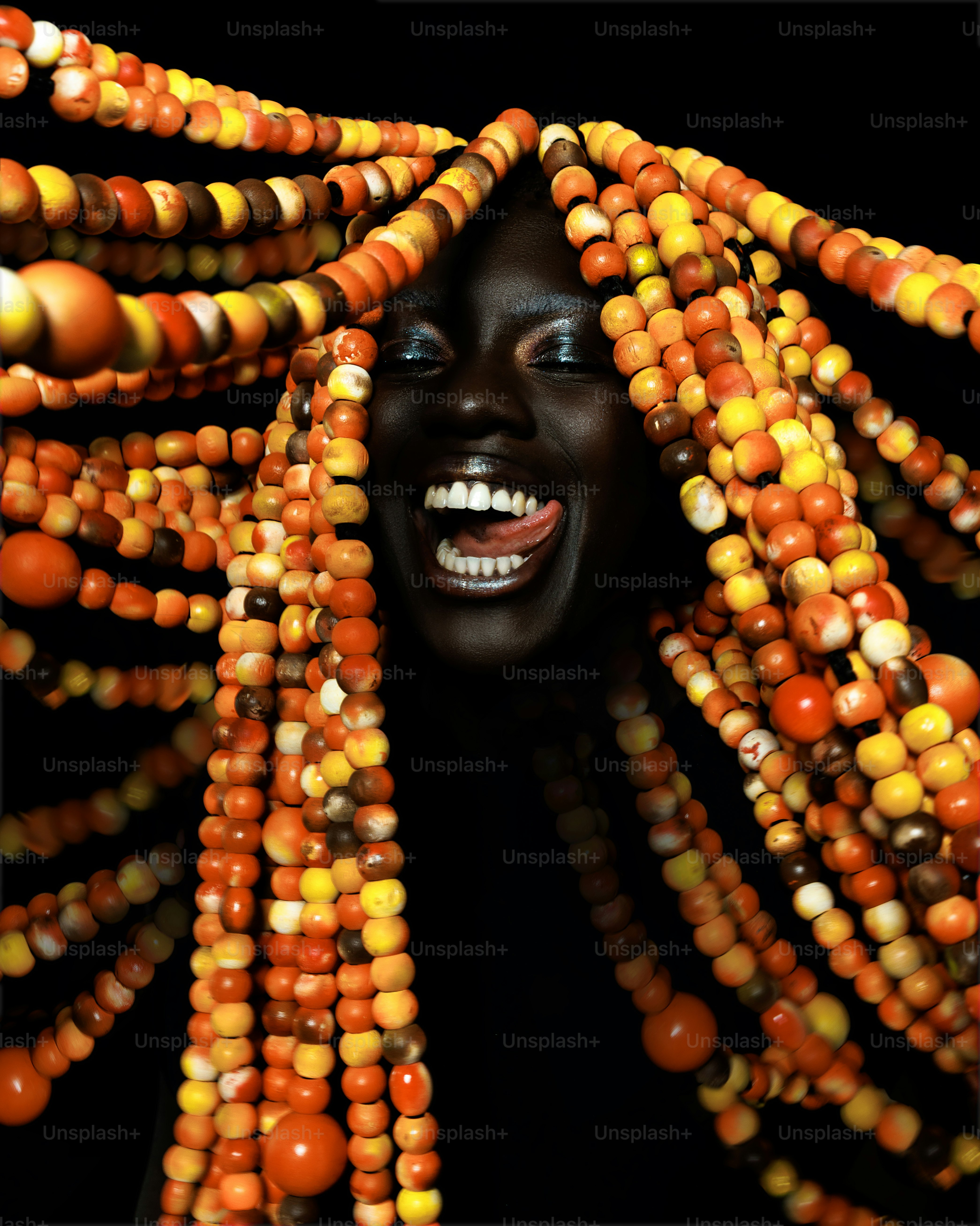 Woman with colorful beaded dreadlocks against black background