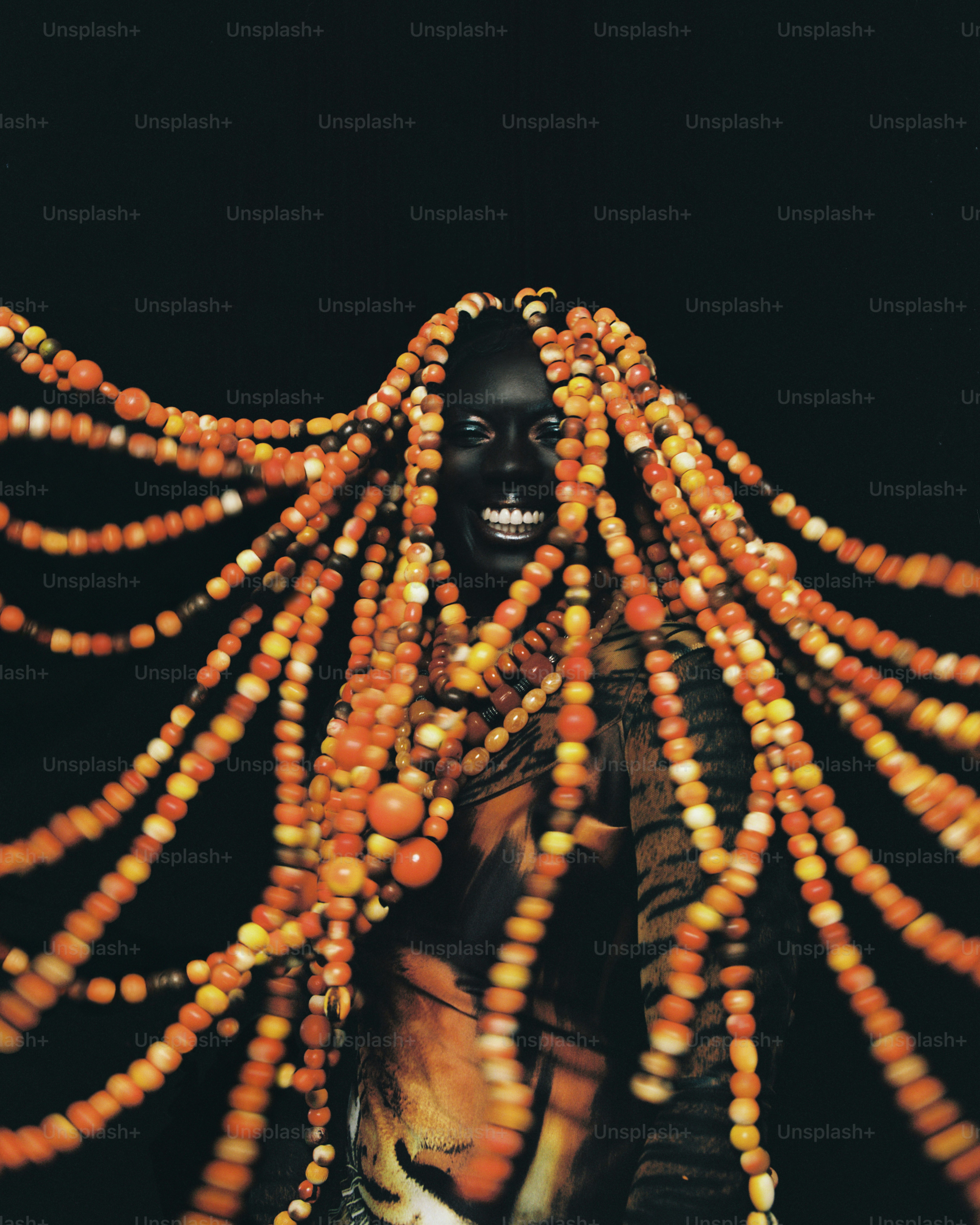 Person with orange beaded dreadlocks and tiger print shirt