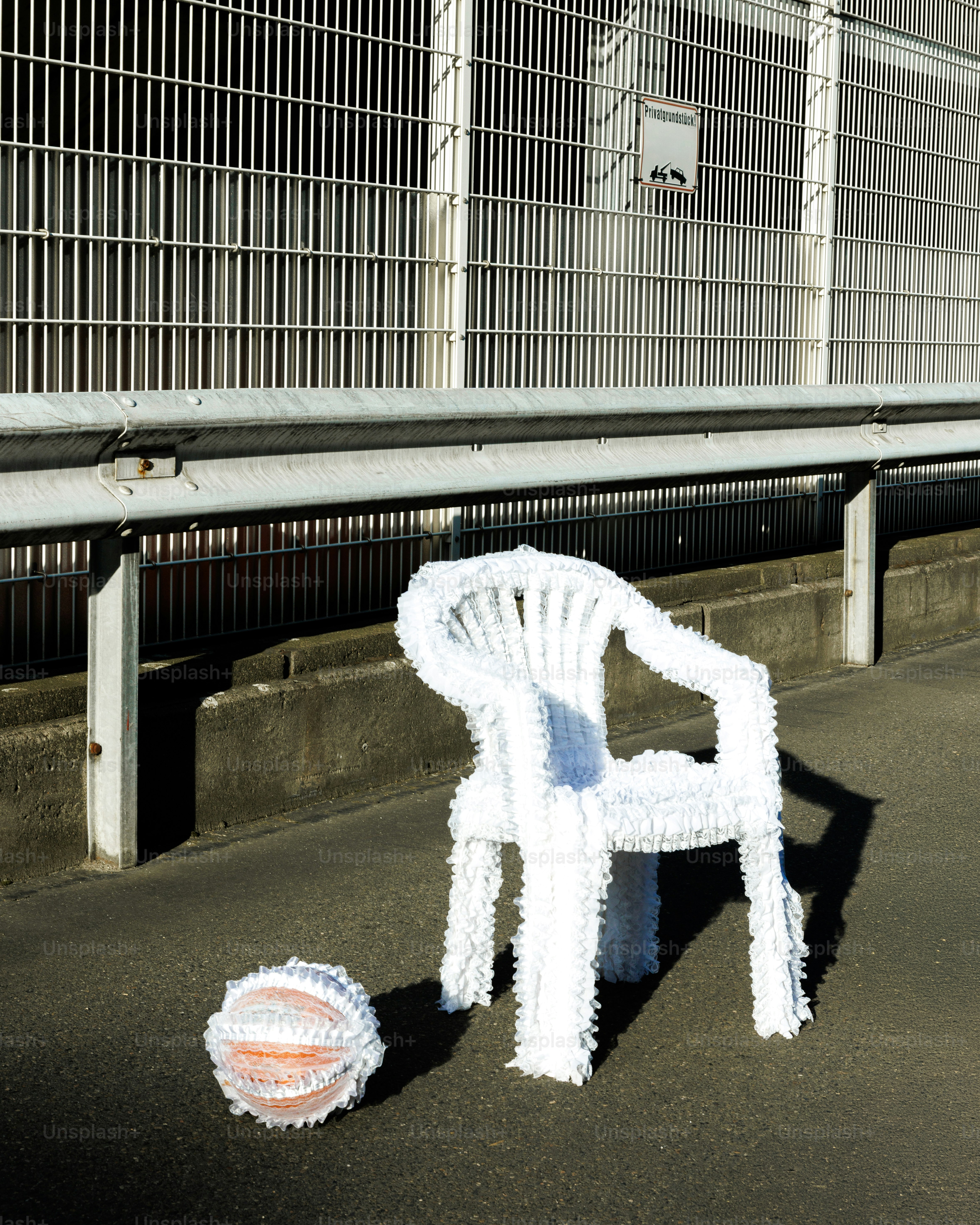 Weißer Stuhl und Ball auf Bürgersteig