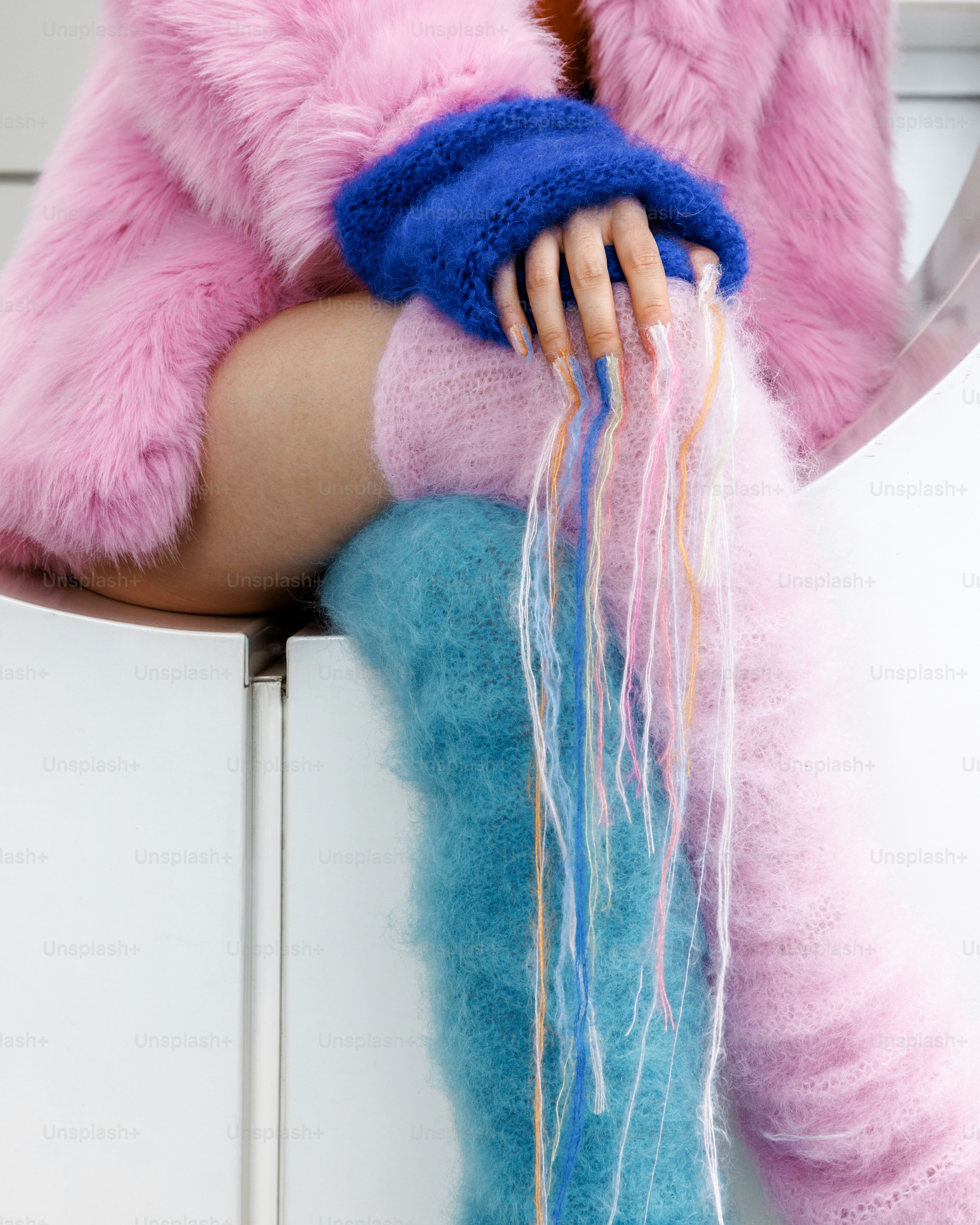 Person wearing pink fur coat and blue leg warmers.