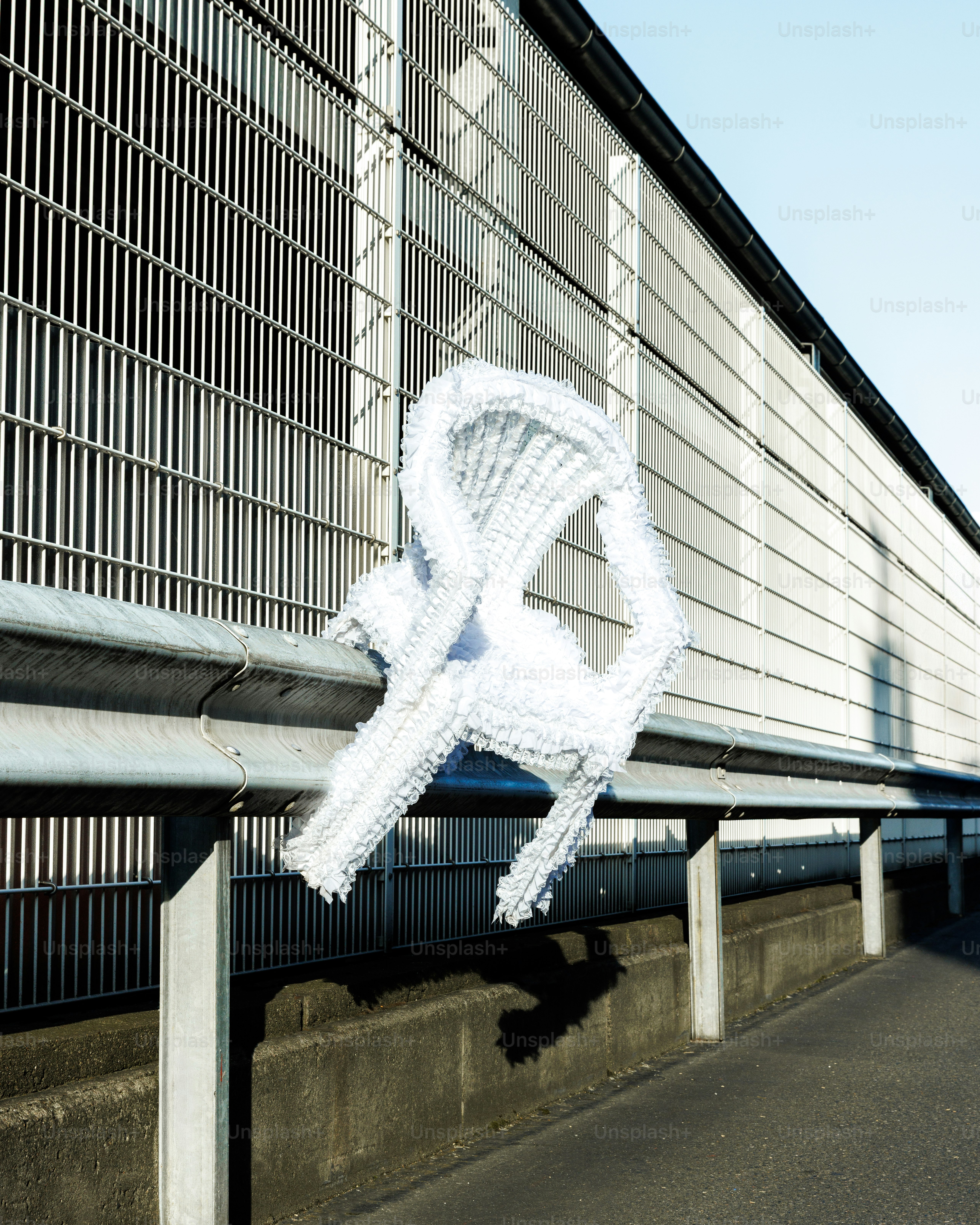 Weiße abstrakte Skulptur auf Metallgeländer im Freien.