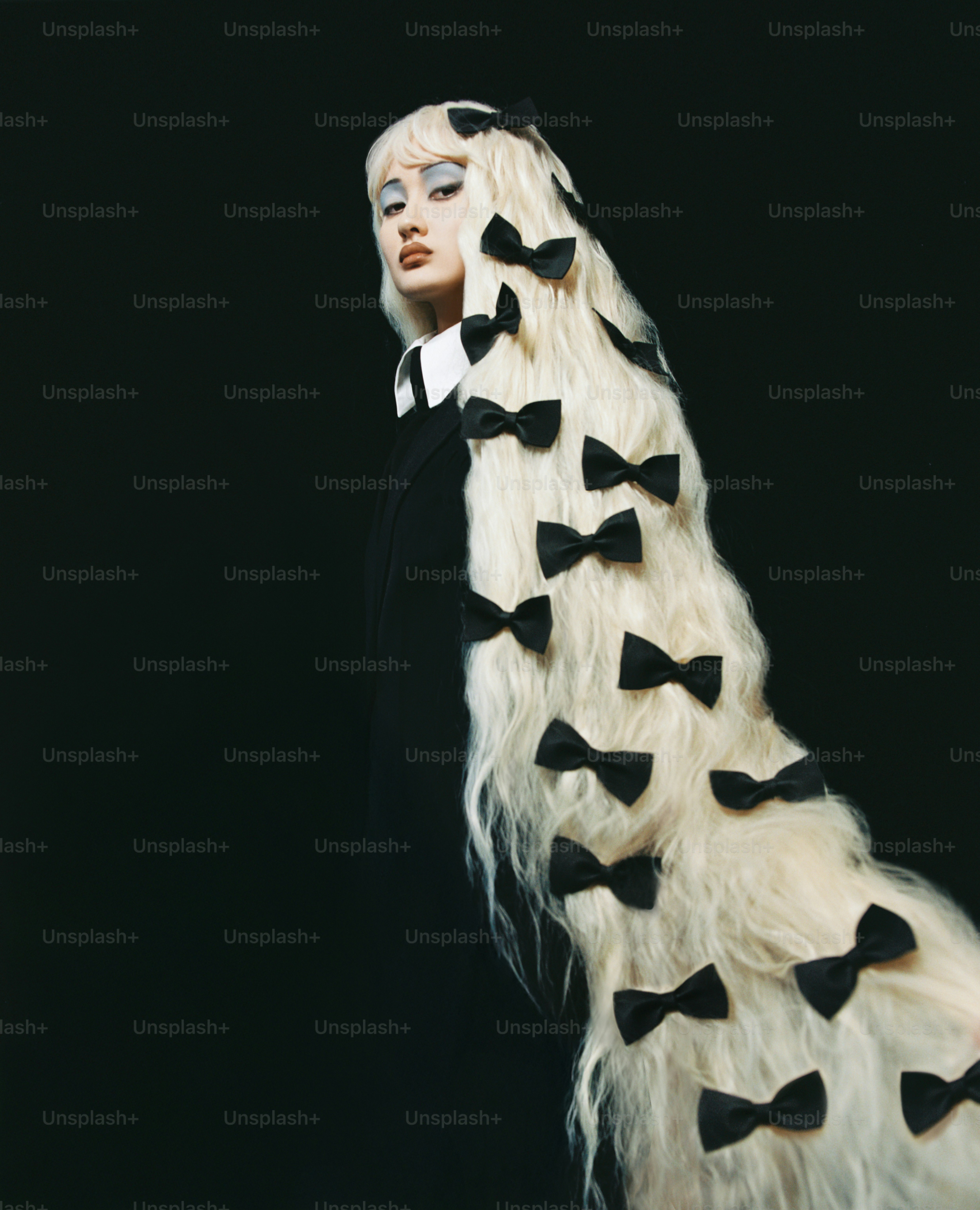 Frau mit langen blonden Haaren, die mit schwarzen Schleifen verziert sind