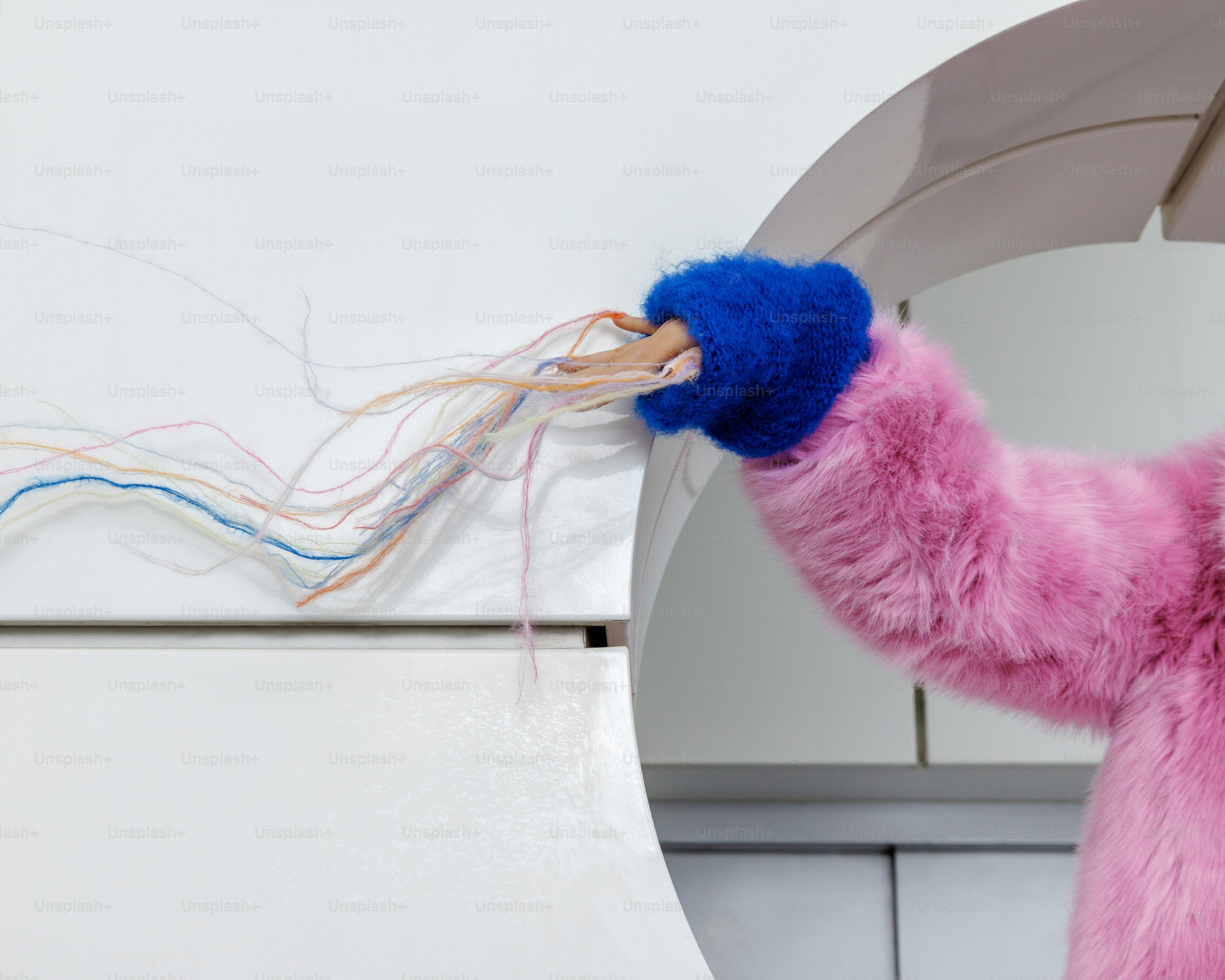 Bras en fourrure rose avec gant bleu qui maintient les fils