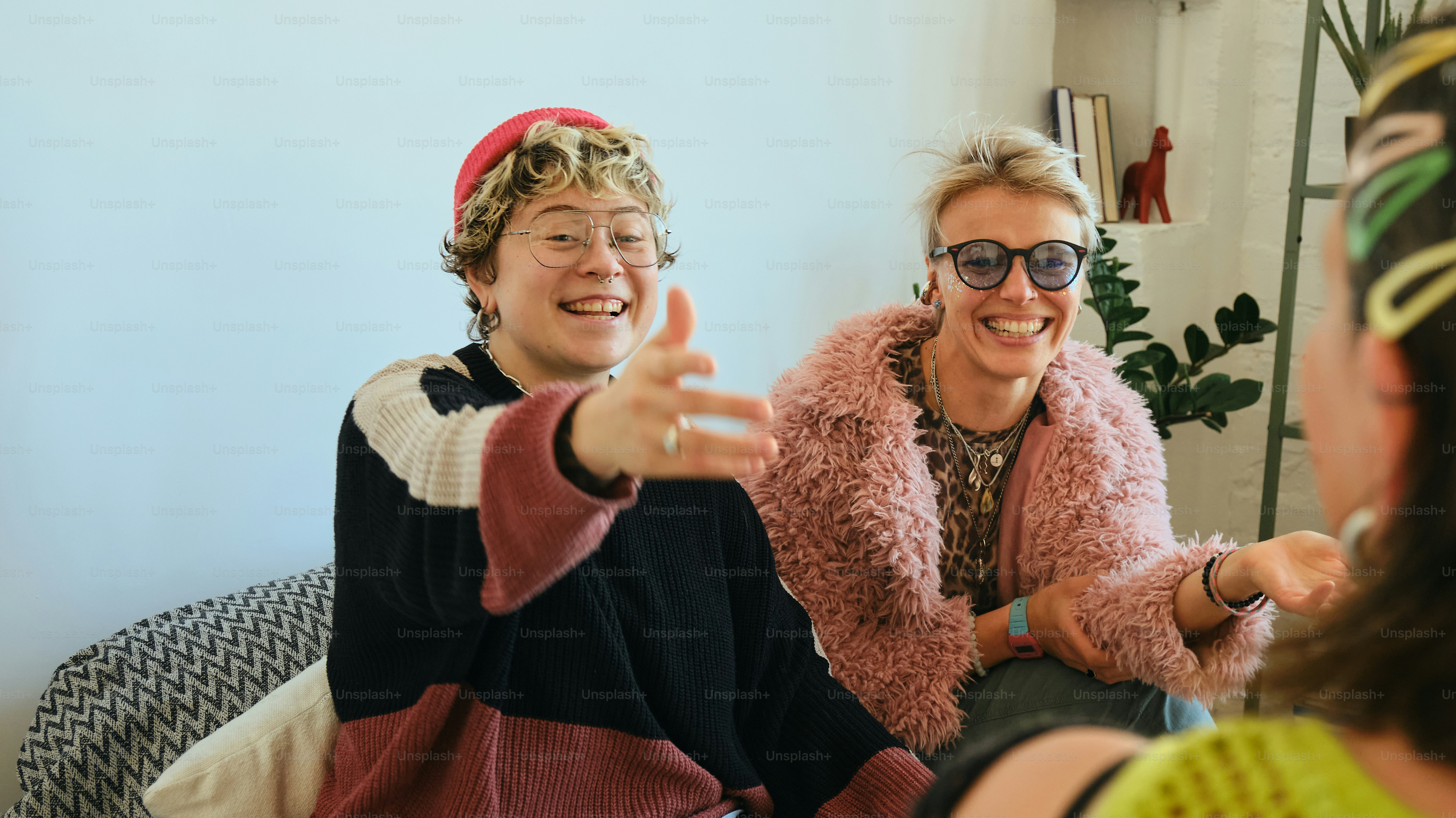 Three friends laughing and talking together indoors.