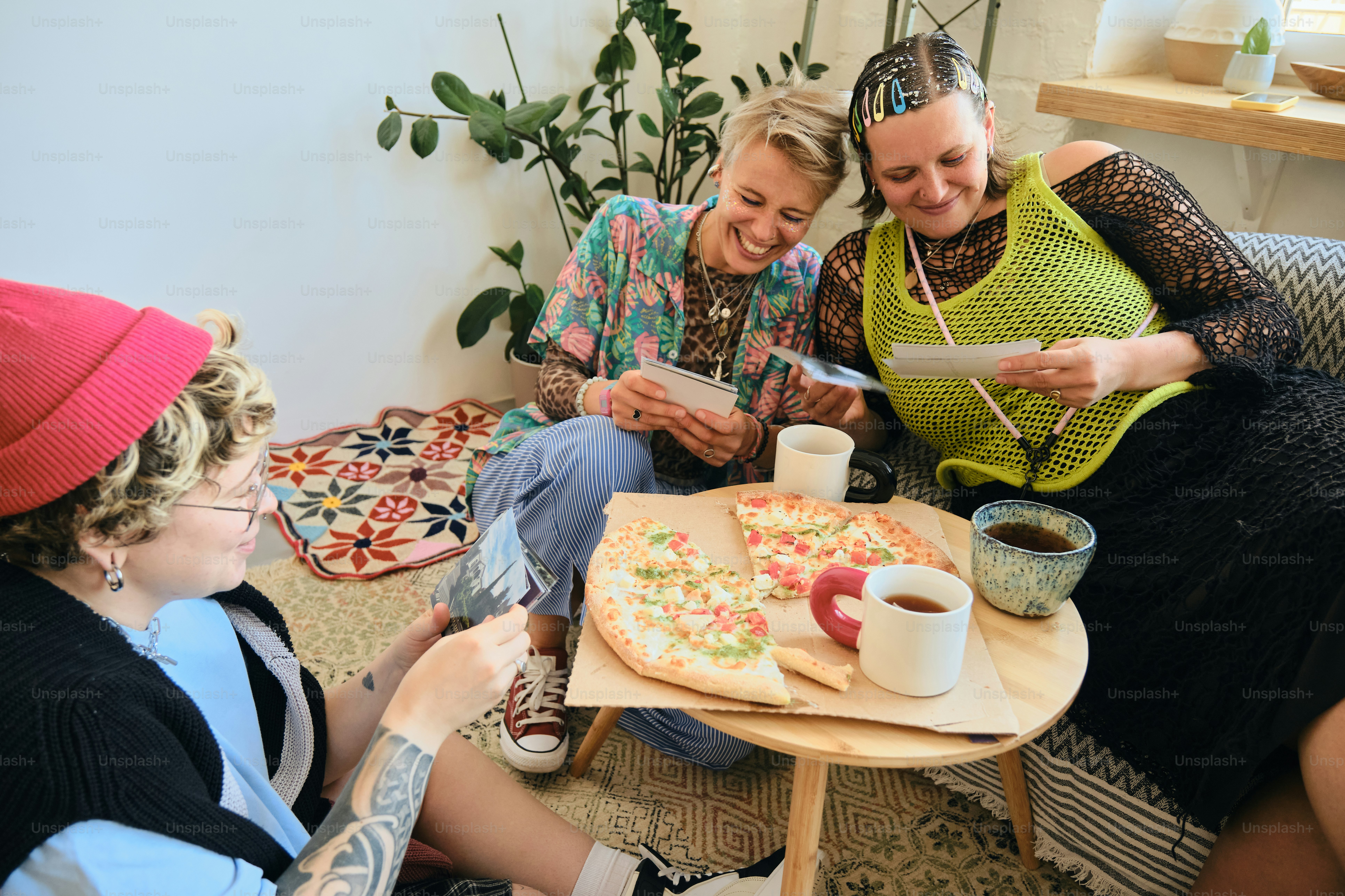 Three friends share pizza and look at photos.