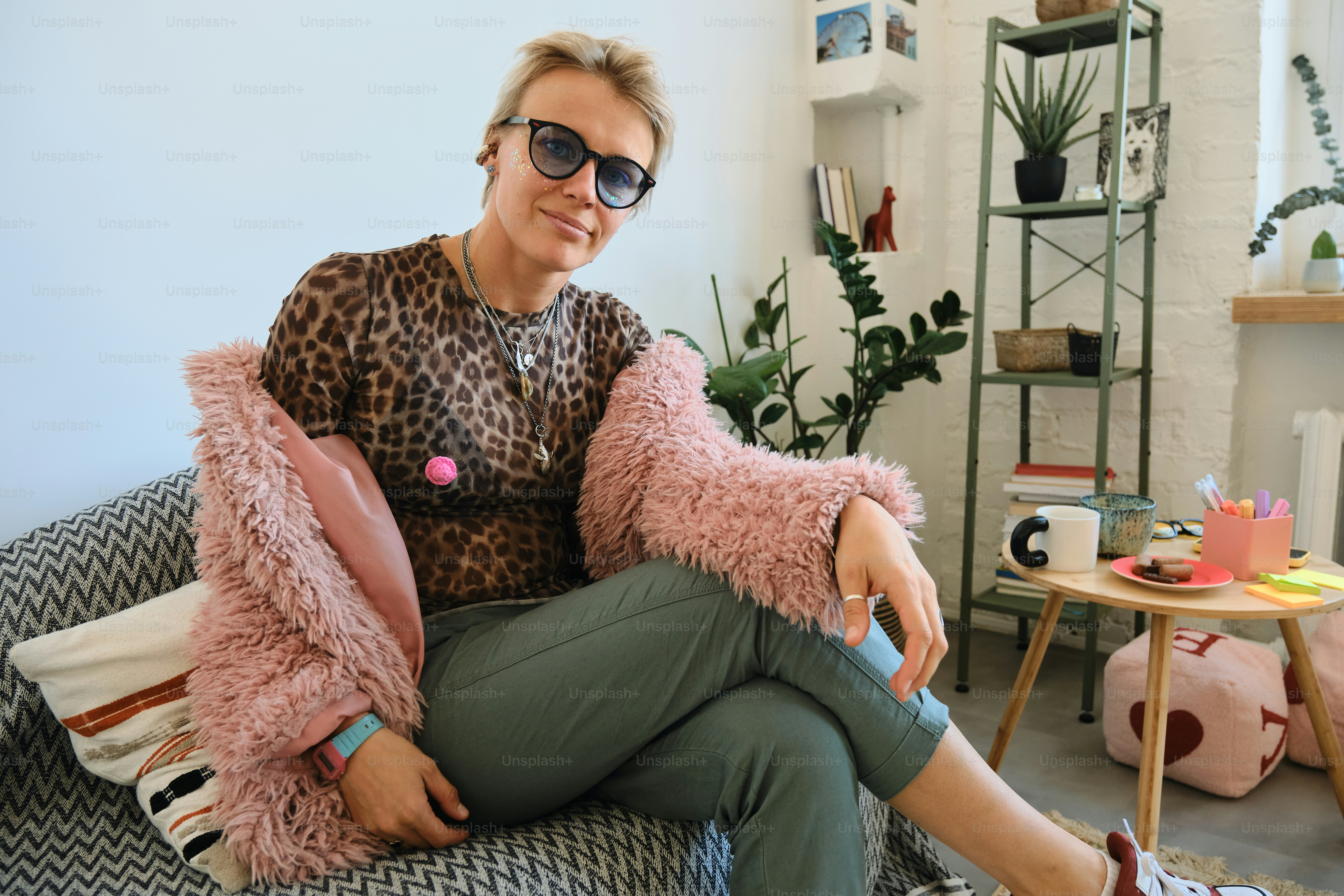 Woman in leopard print and pink jacket sitting indoors.