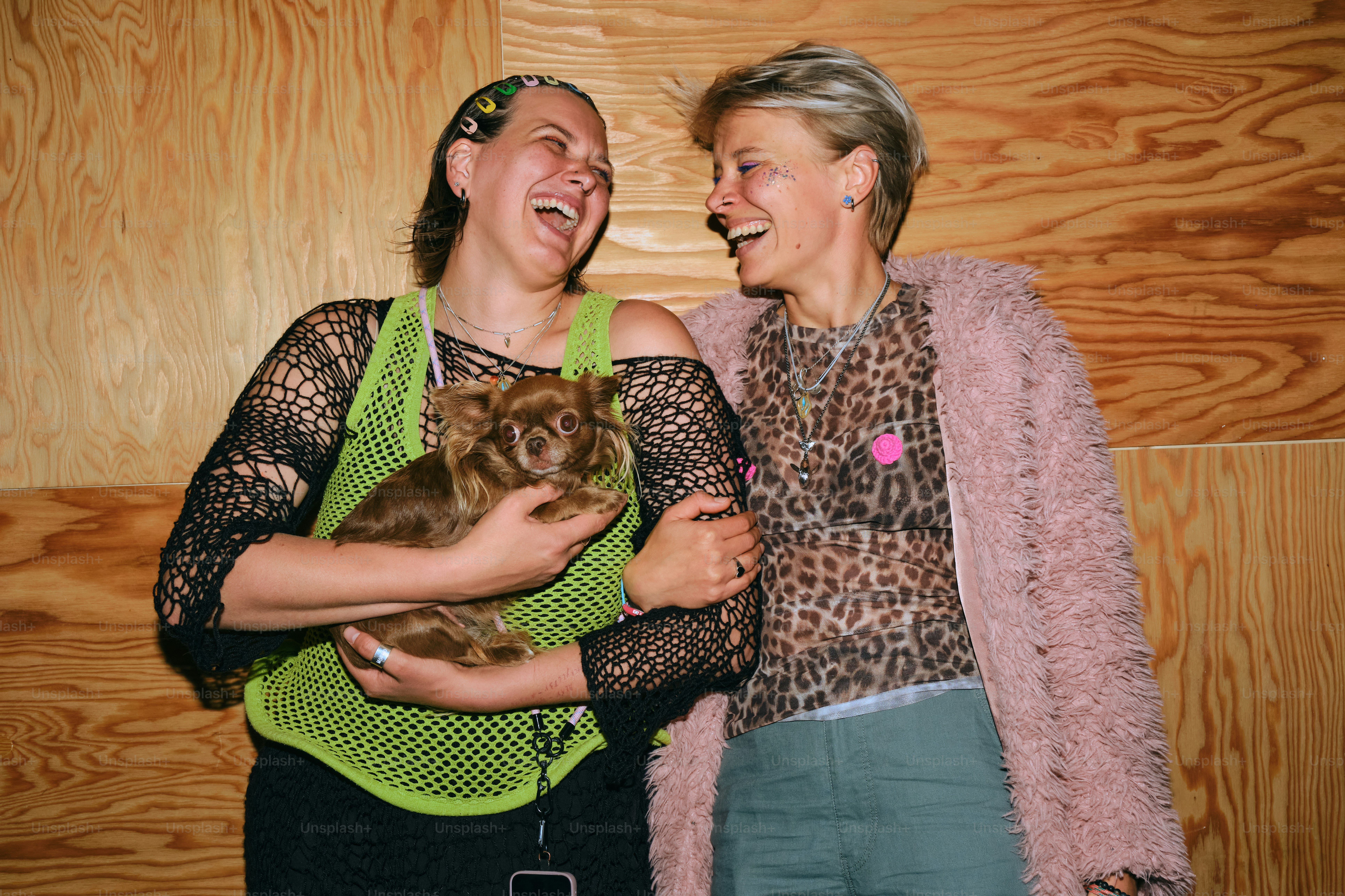 Two women laughing, one holding a small dog.