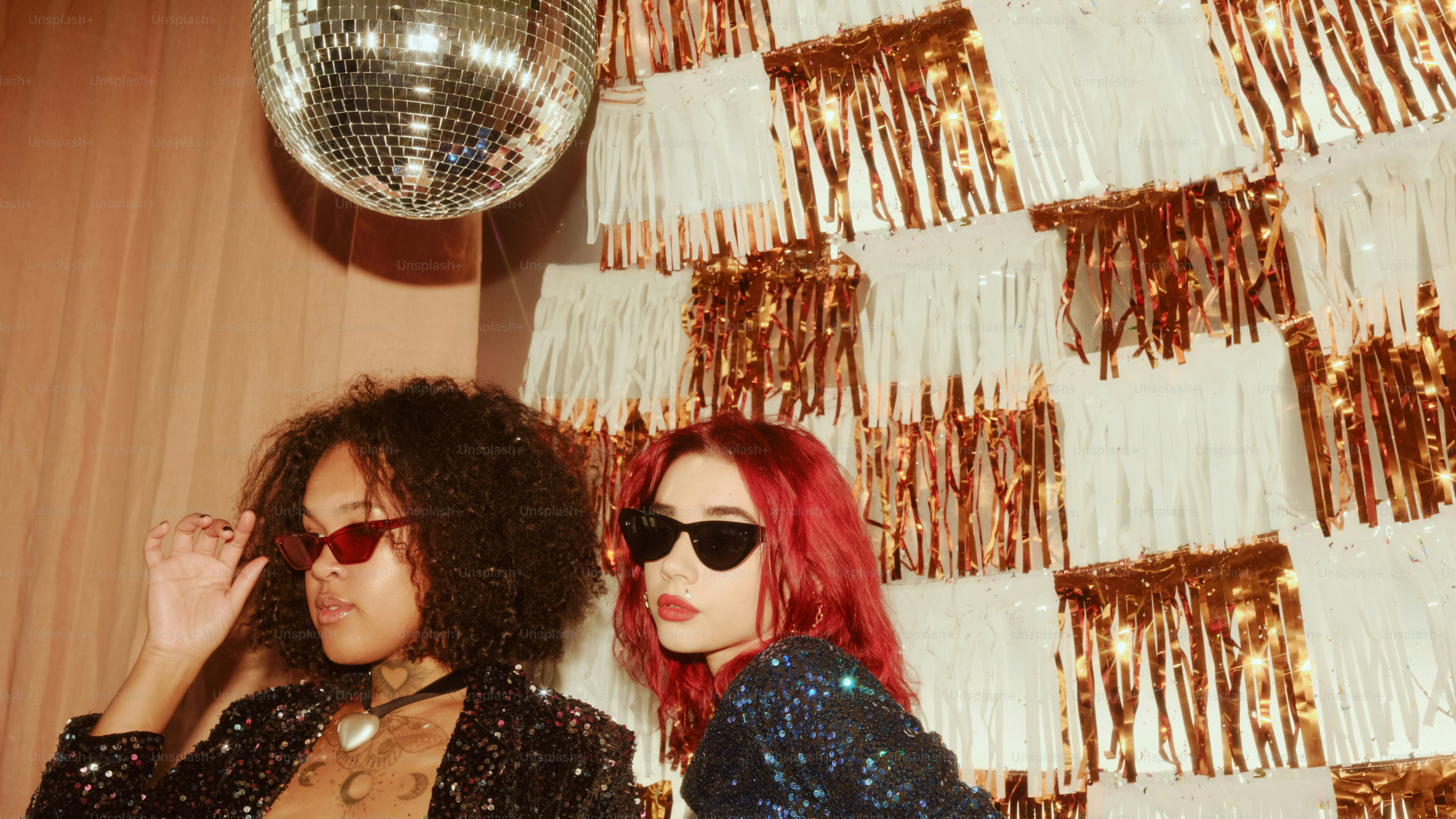 Two women posing under a disco ball
