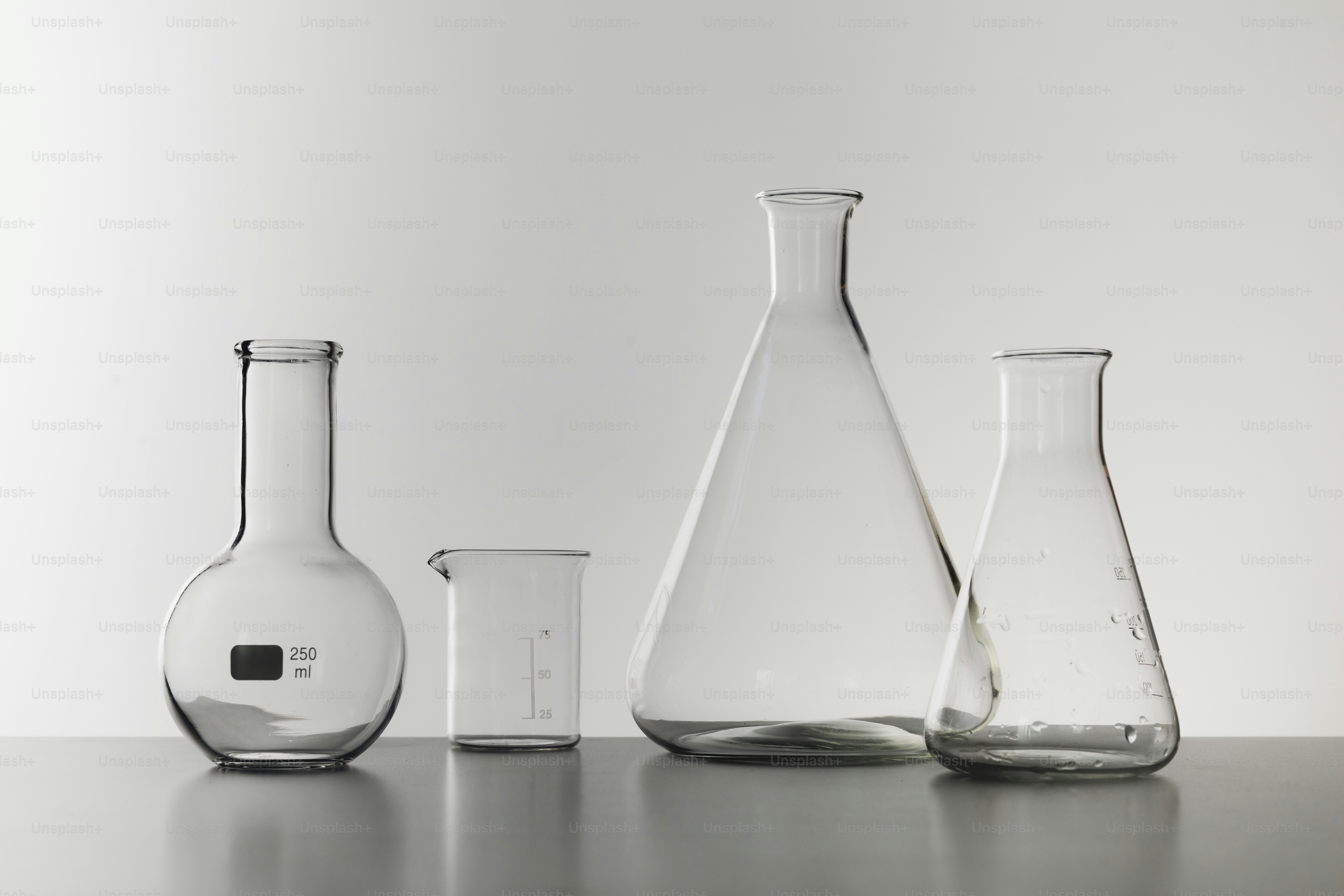 Four empty glass laboratory flasks on a gray surface.