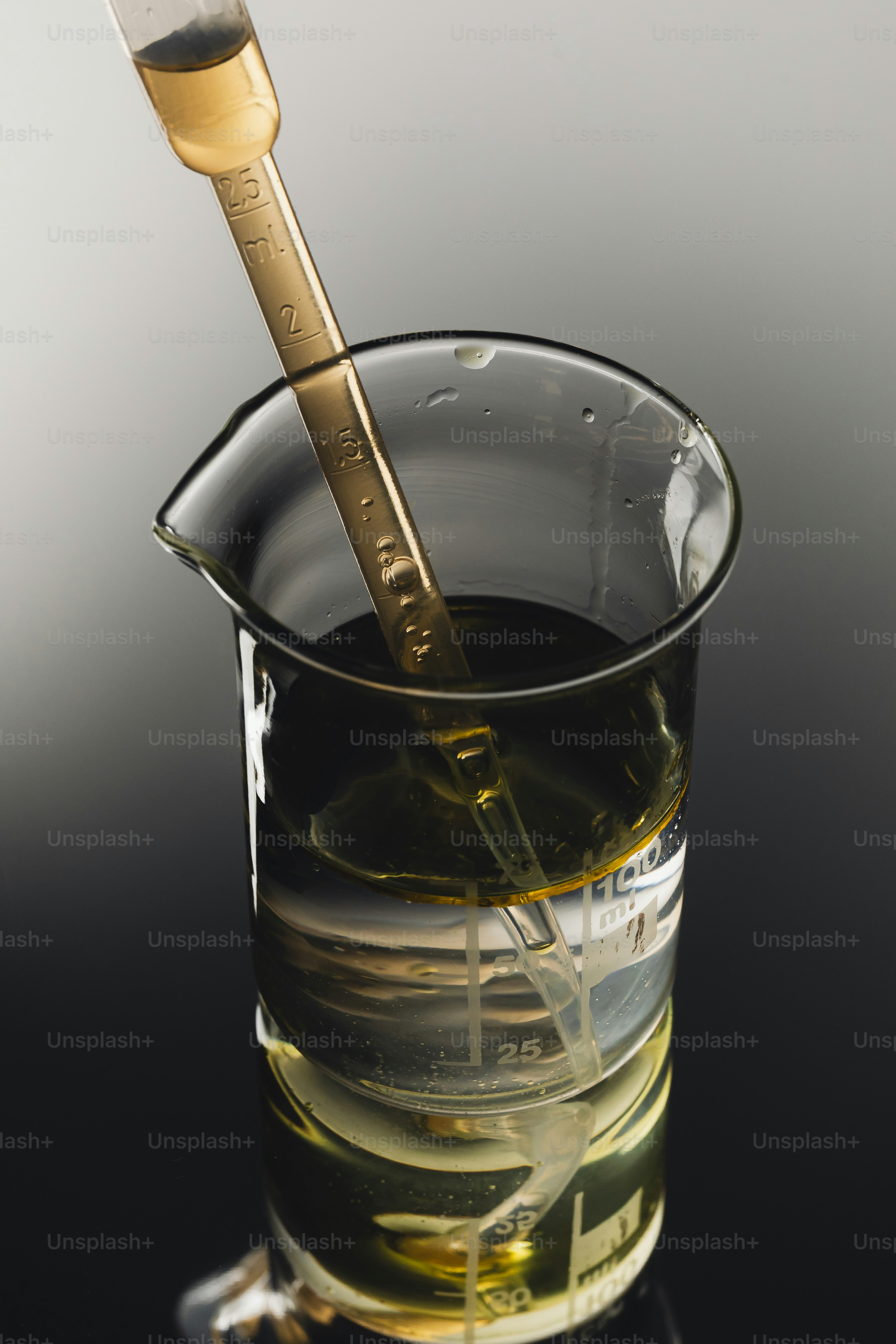 Pipette dropping liquid into beaker with liquid