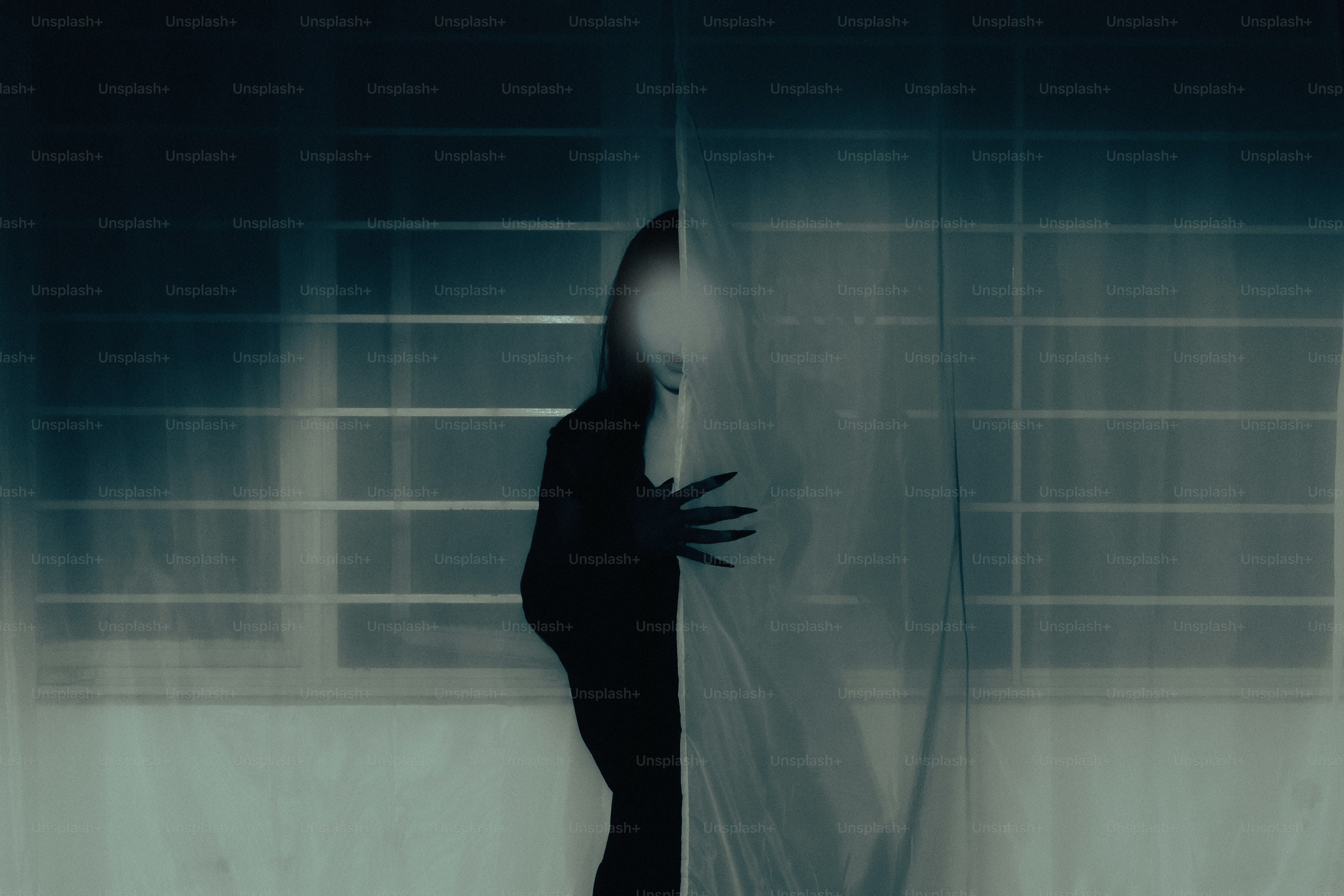 Silhouette of a person peeking through sheer curtains