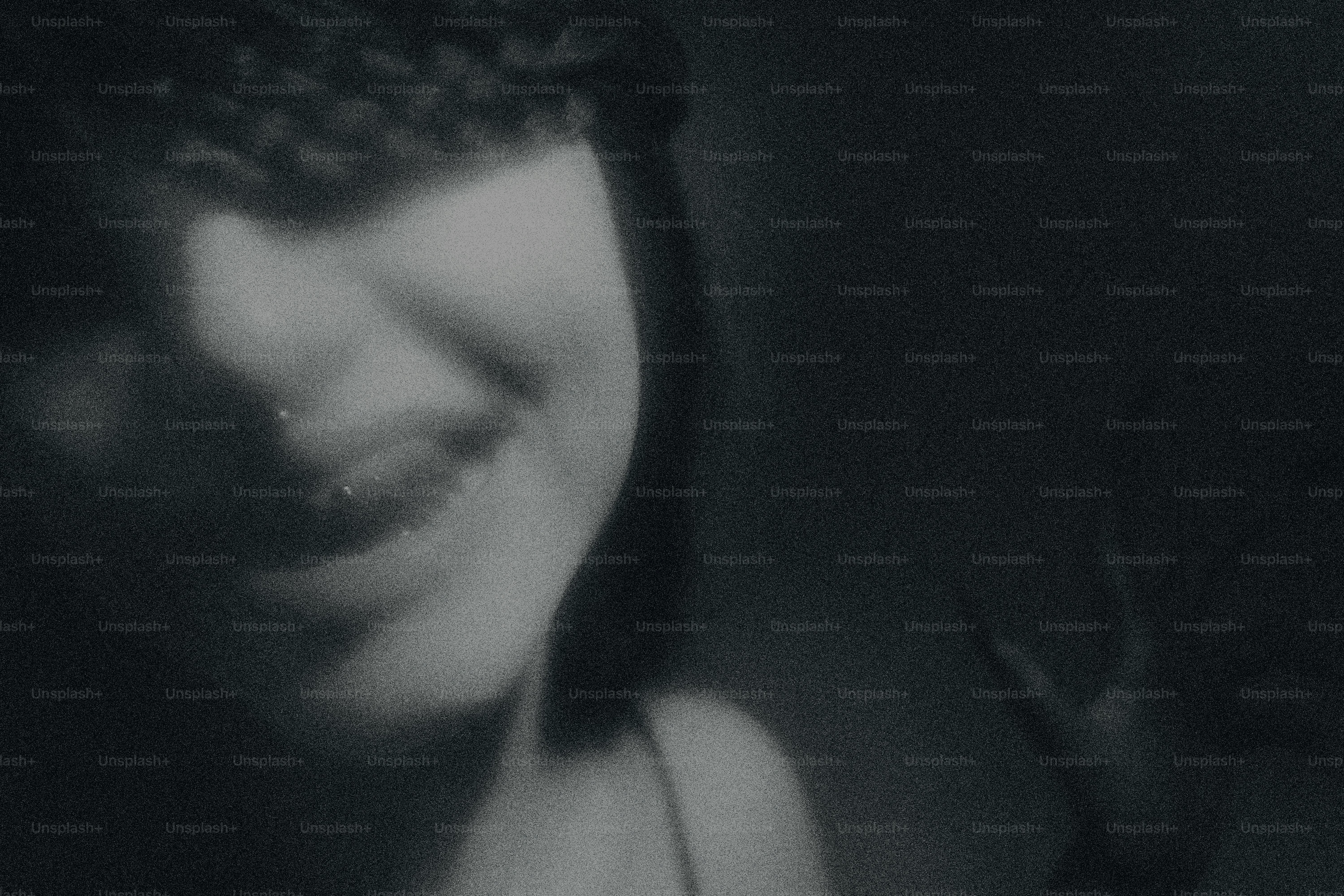 A person smiling with braided hair and a dark background