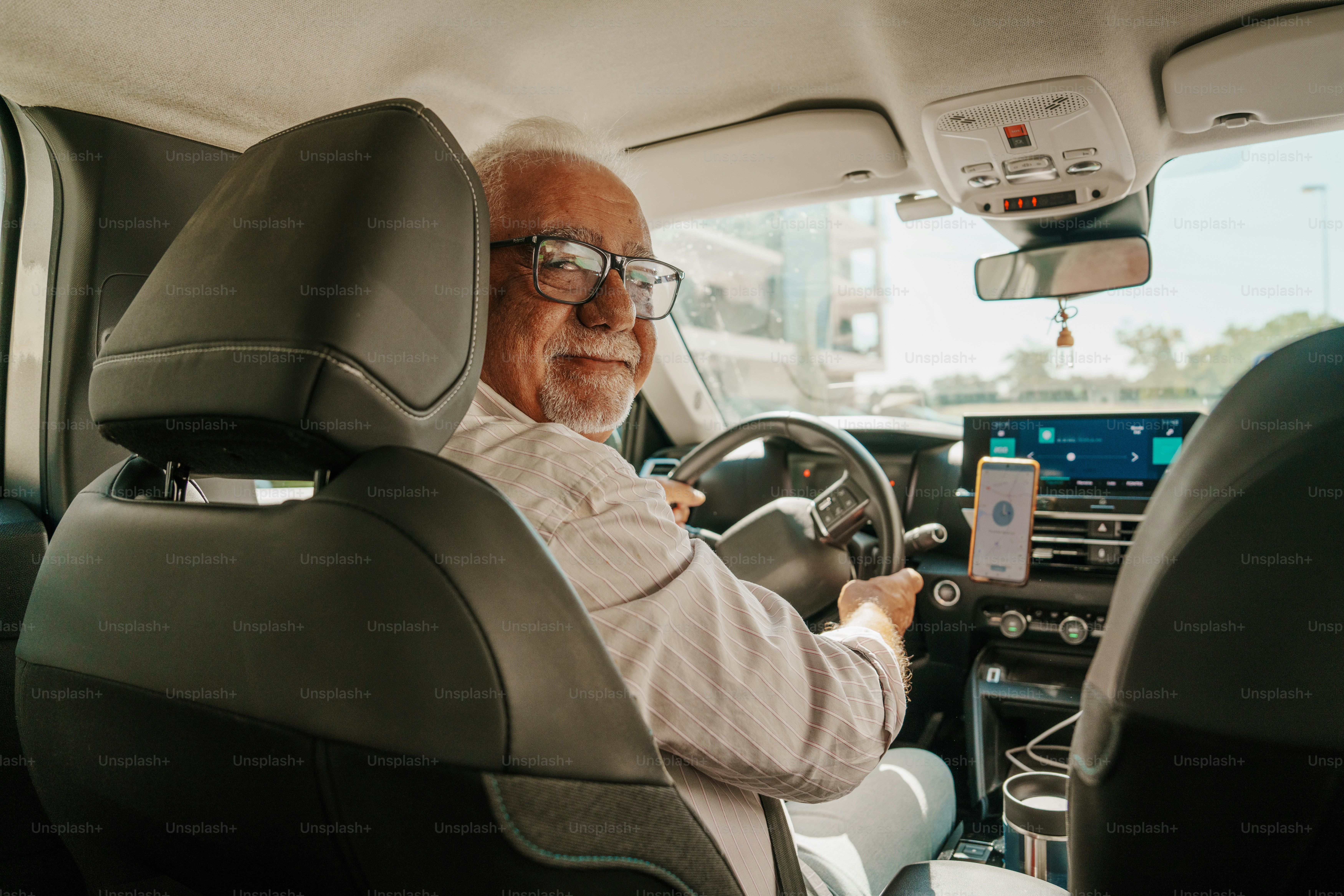 Smiling older man driving a car with phone photo – Technology Image on ...