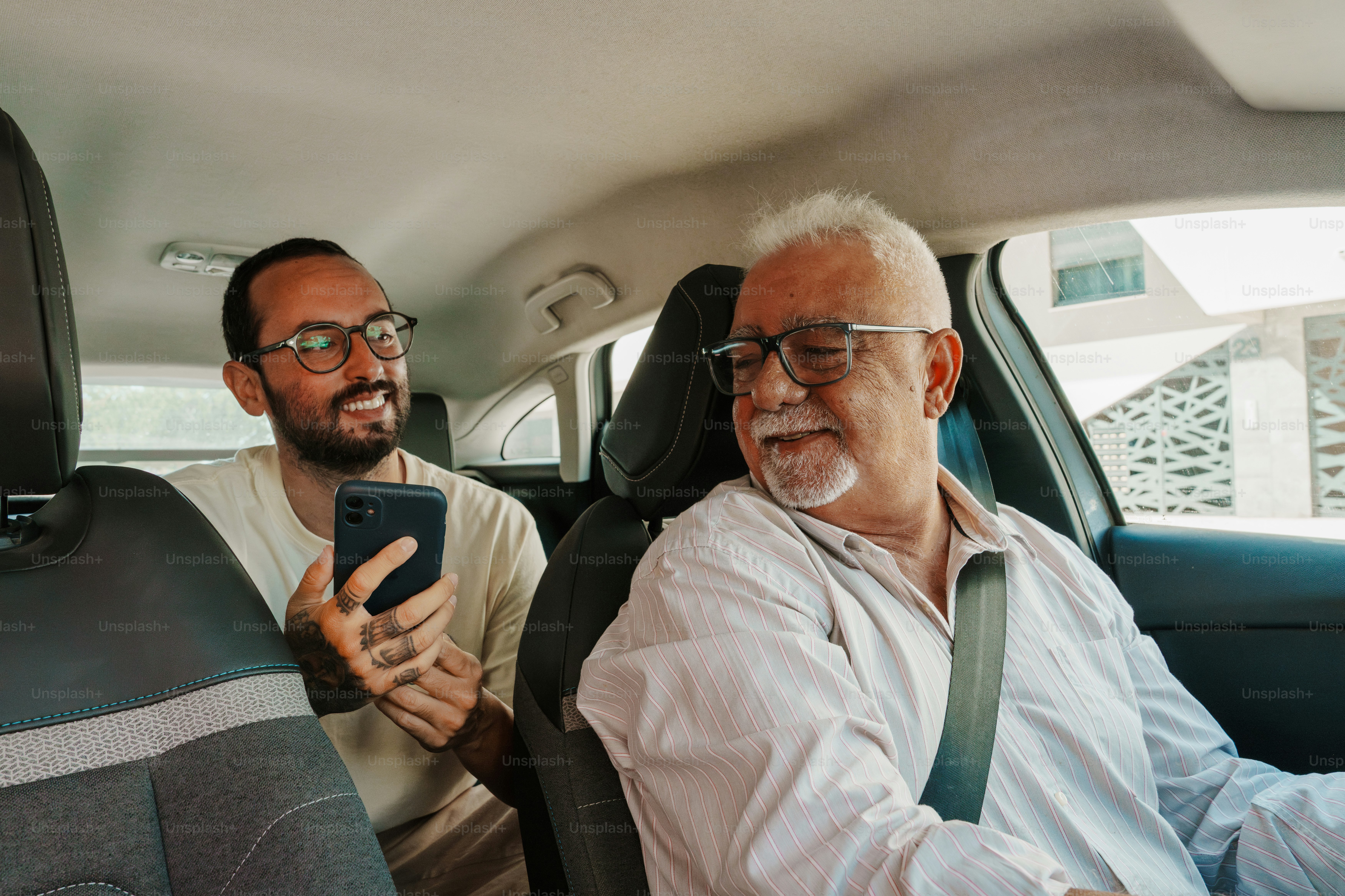 Dos hombres en un automóvil, uno sosteniendo un teléfono