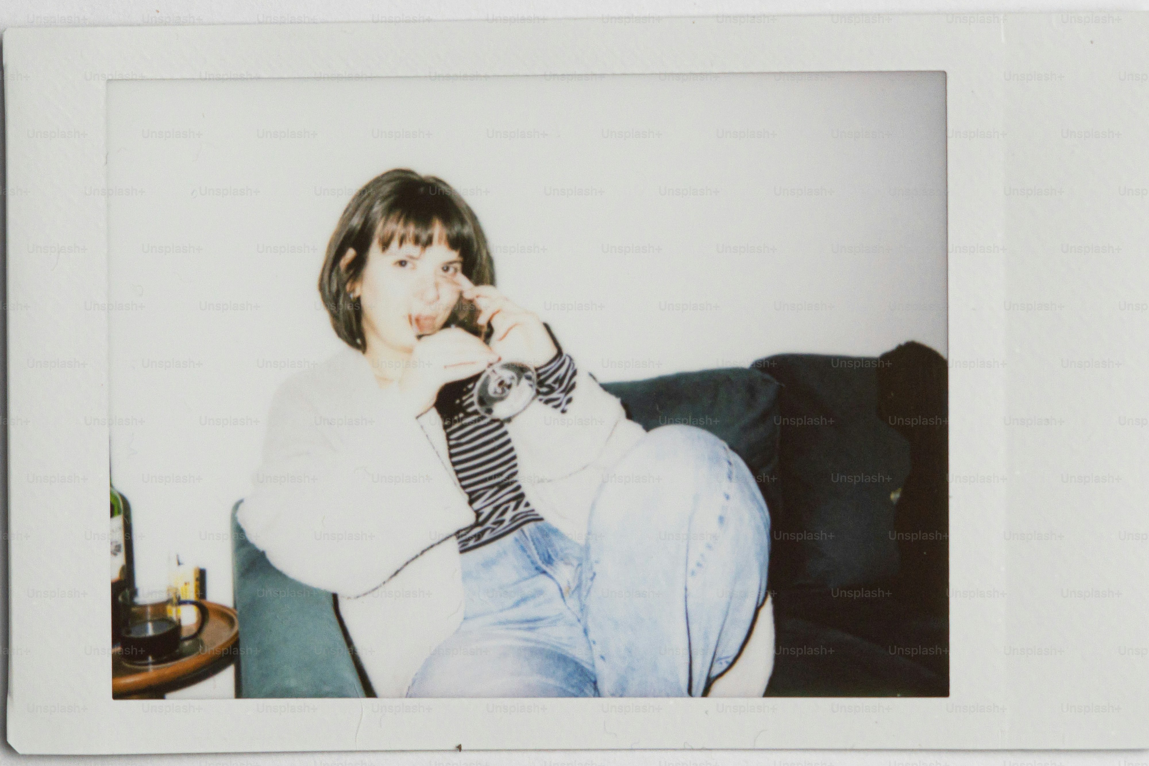 A woman sits on a couch holding a drink.