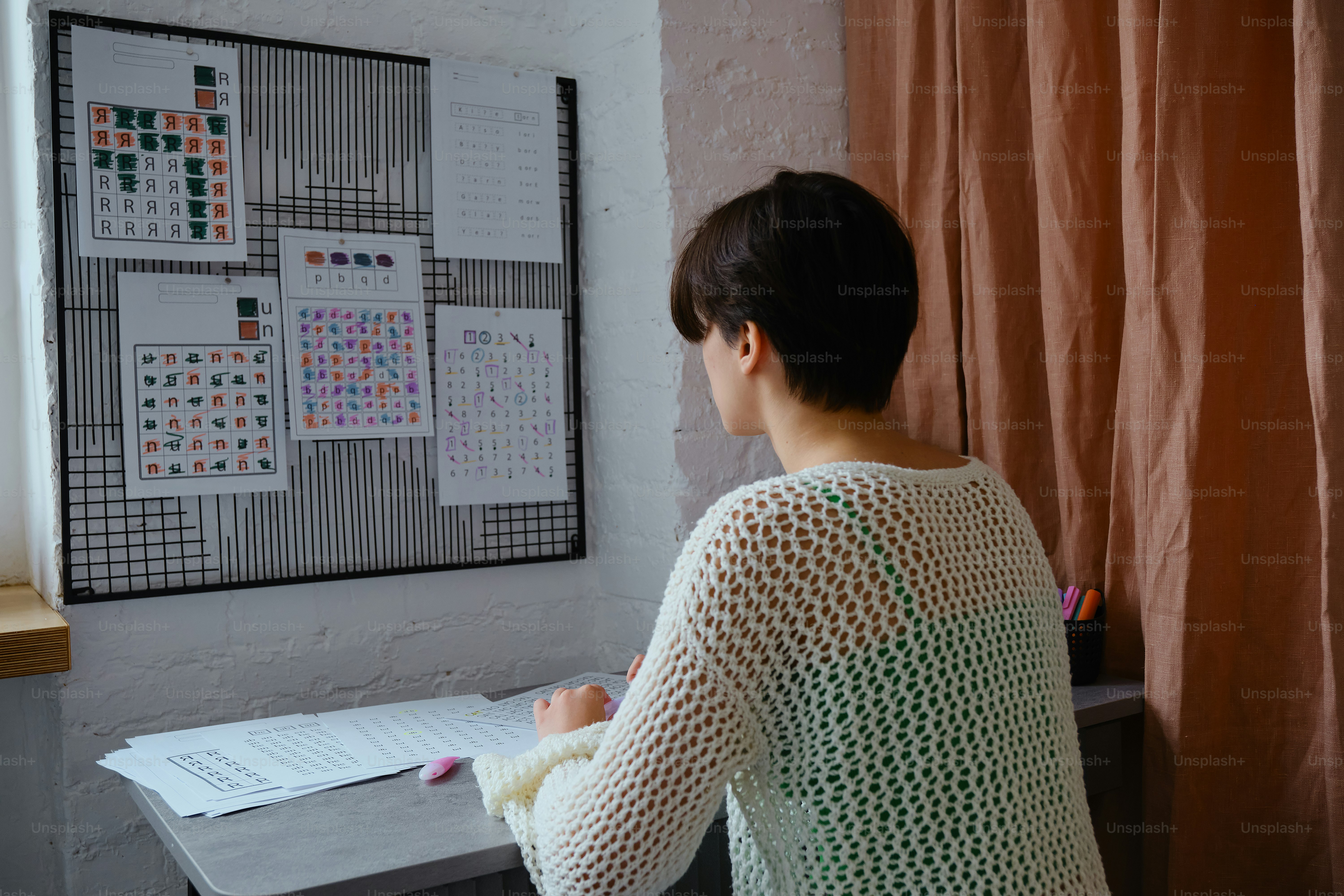 Woman looking at a calendar grid on a wall.