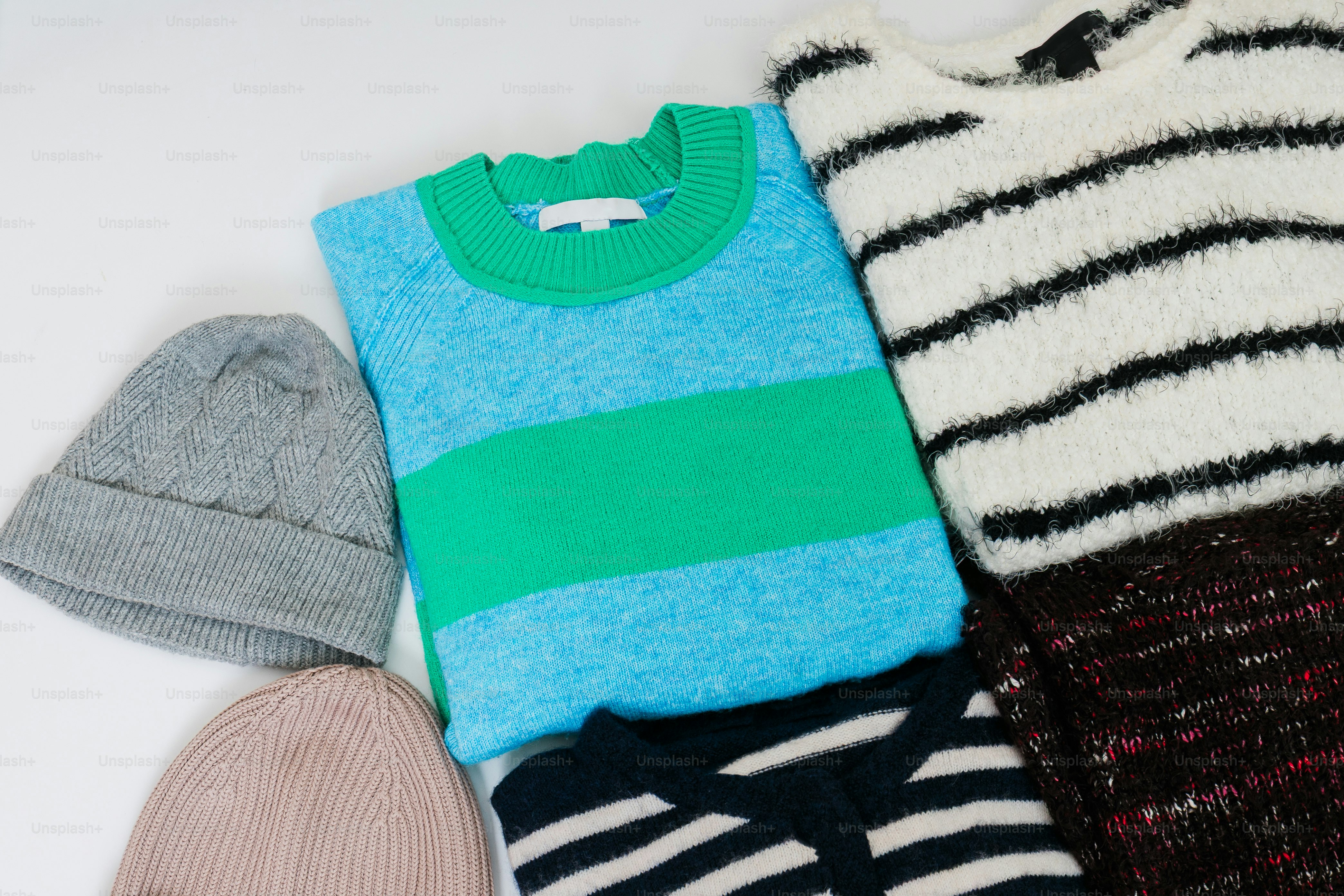 Colorful knitwear and hats laid flat on white background