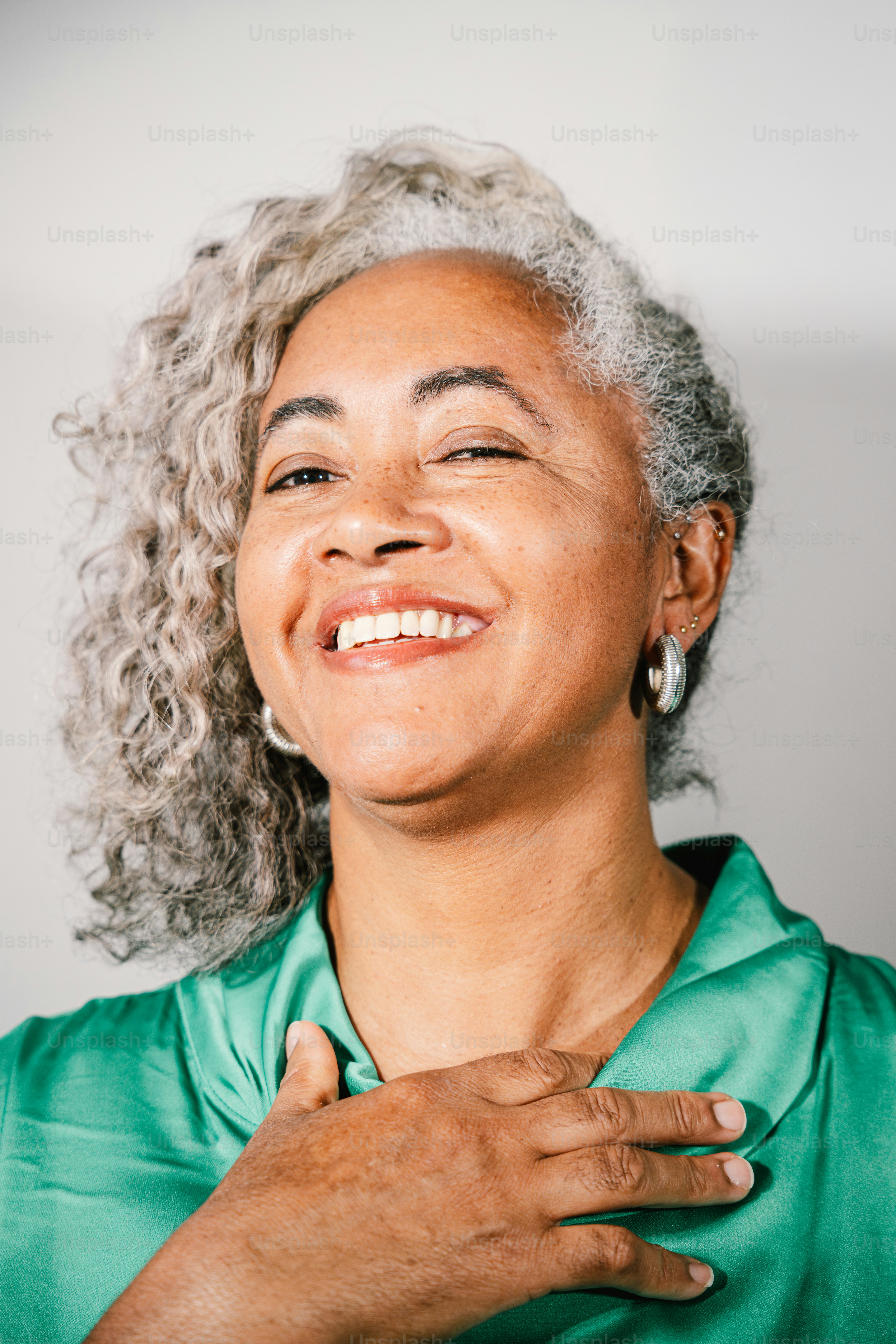 A smiling woman with gray curly hair and green shirt. photo – Woman ...