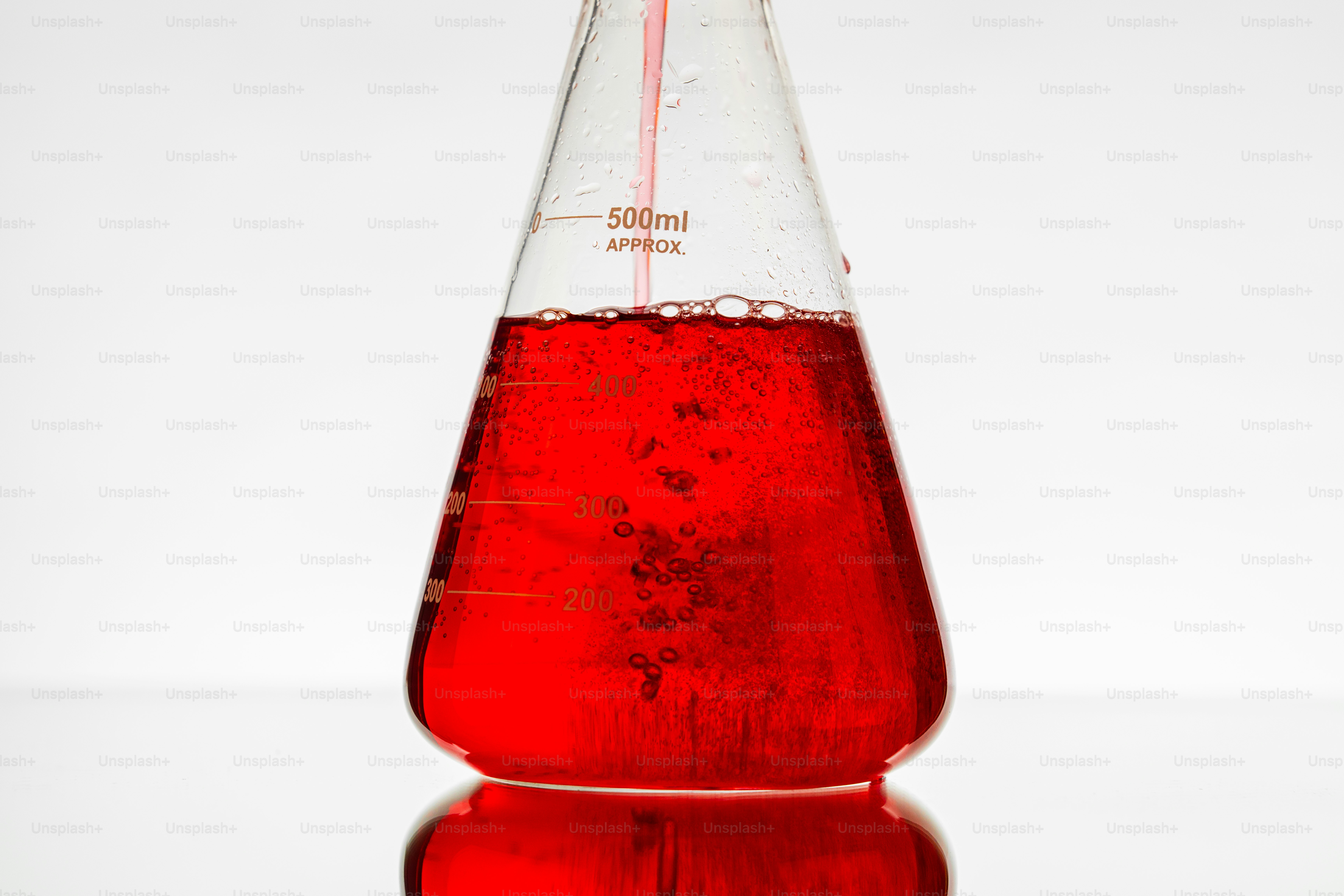 Red liquid being poured into an erlenmeyer flask.