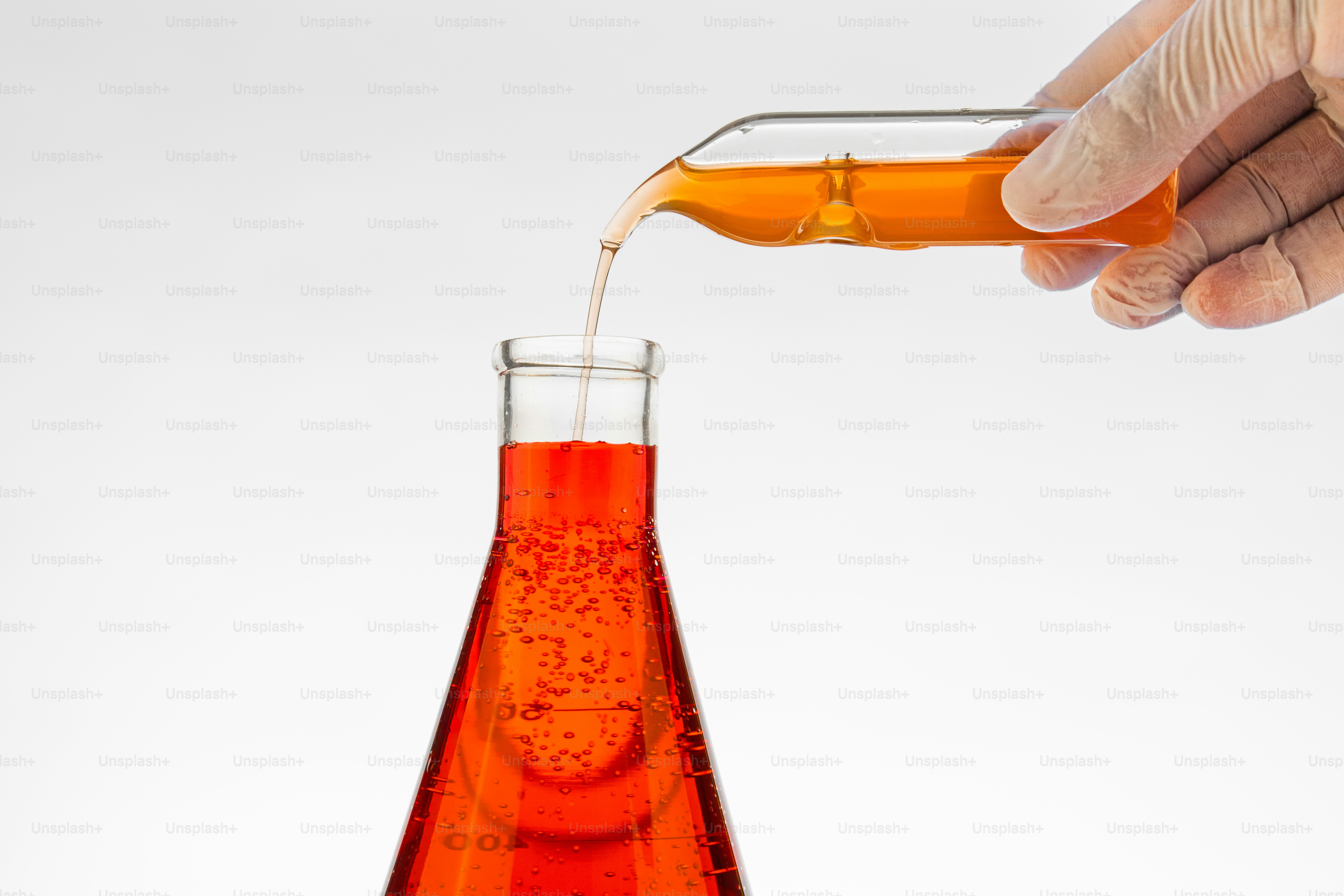 Hand pouring orange liquid into flask