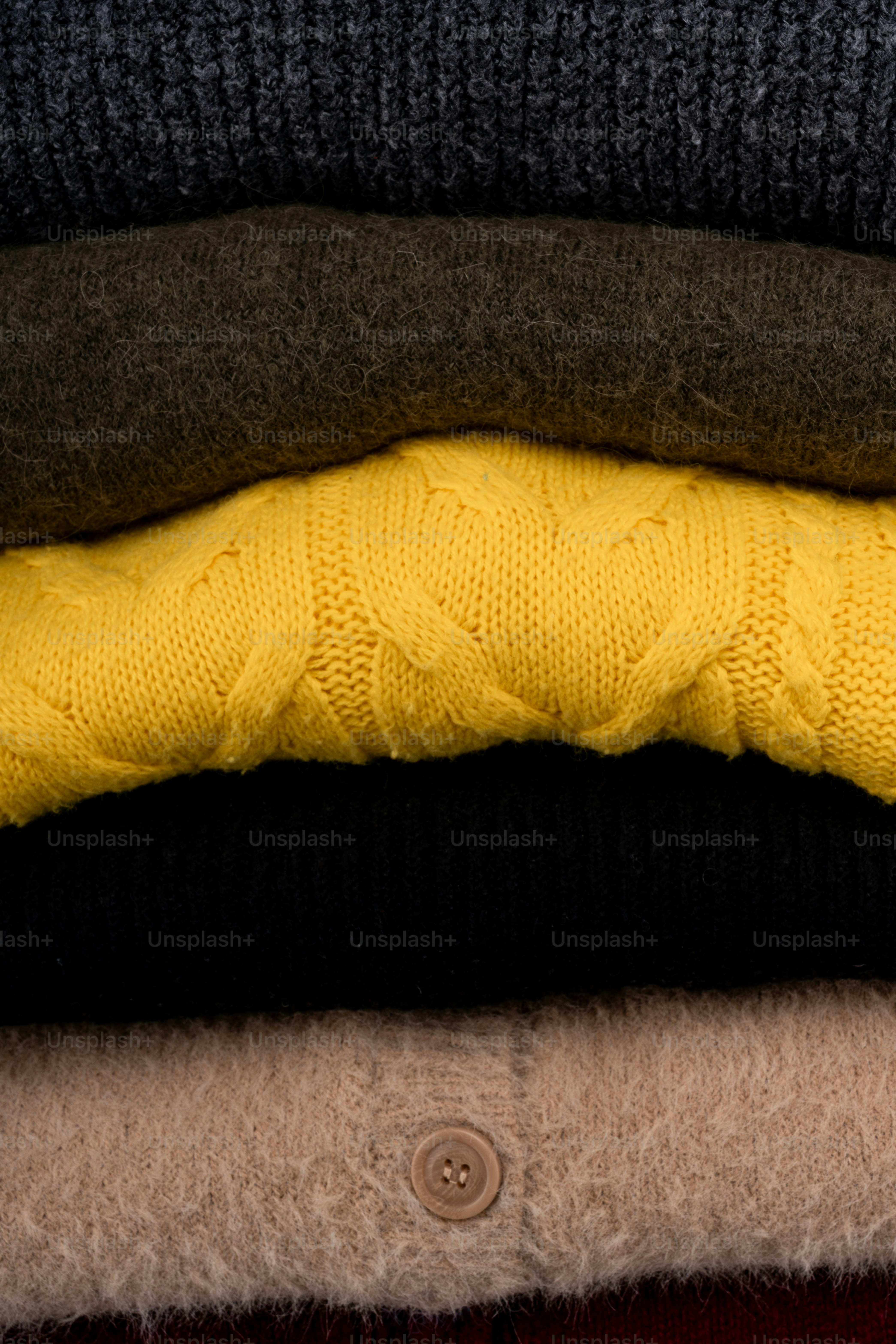 Stack of folded knit sweaters in various colors.