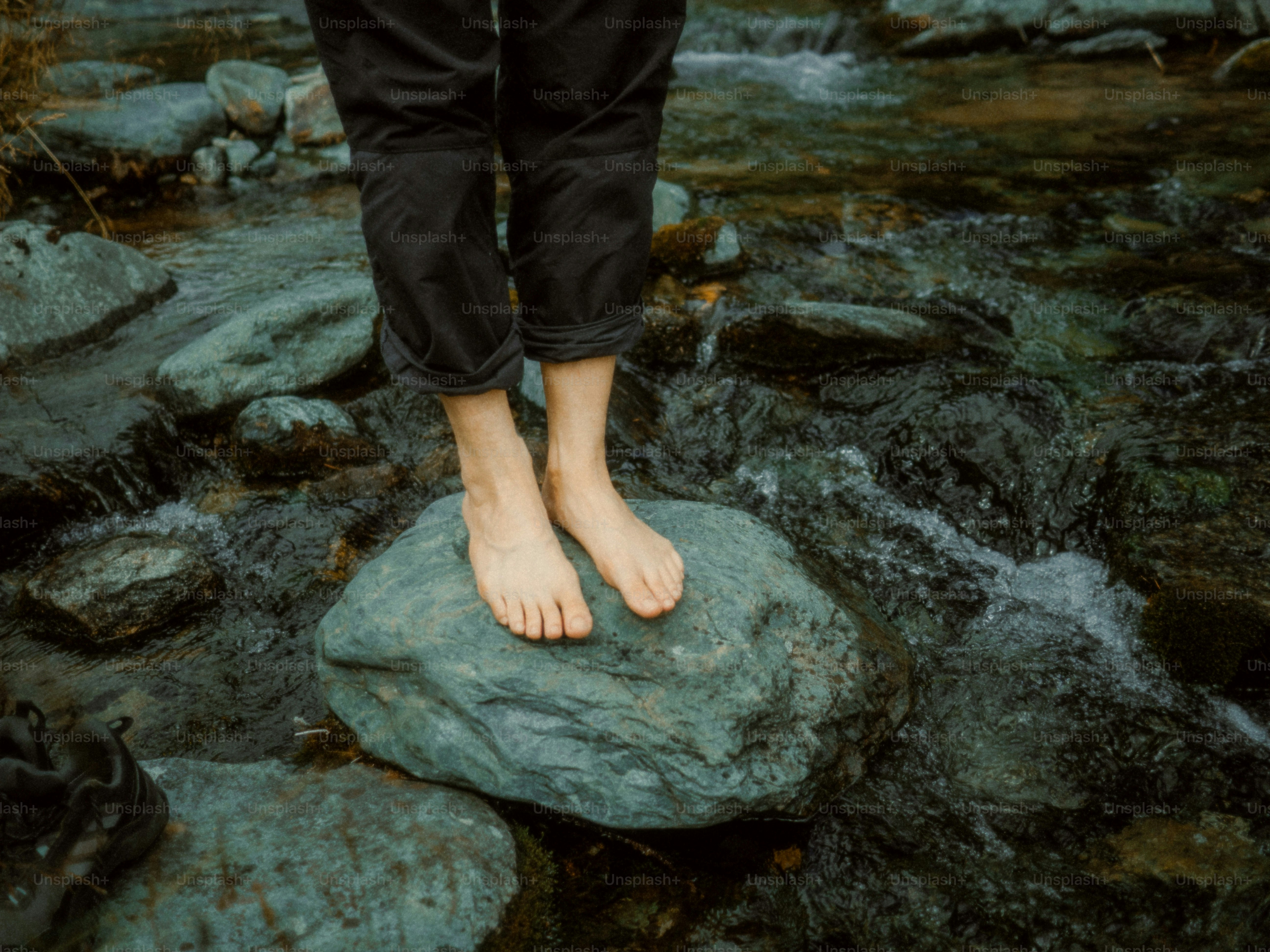 Bare feet standing on a rock in a stream