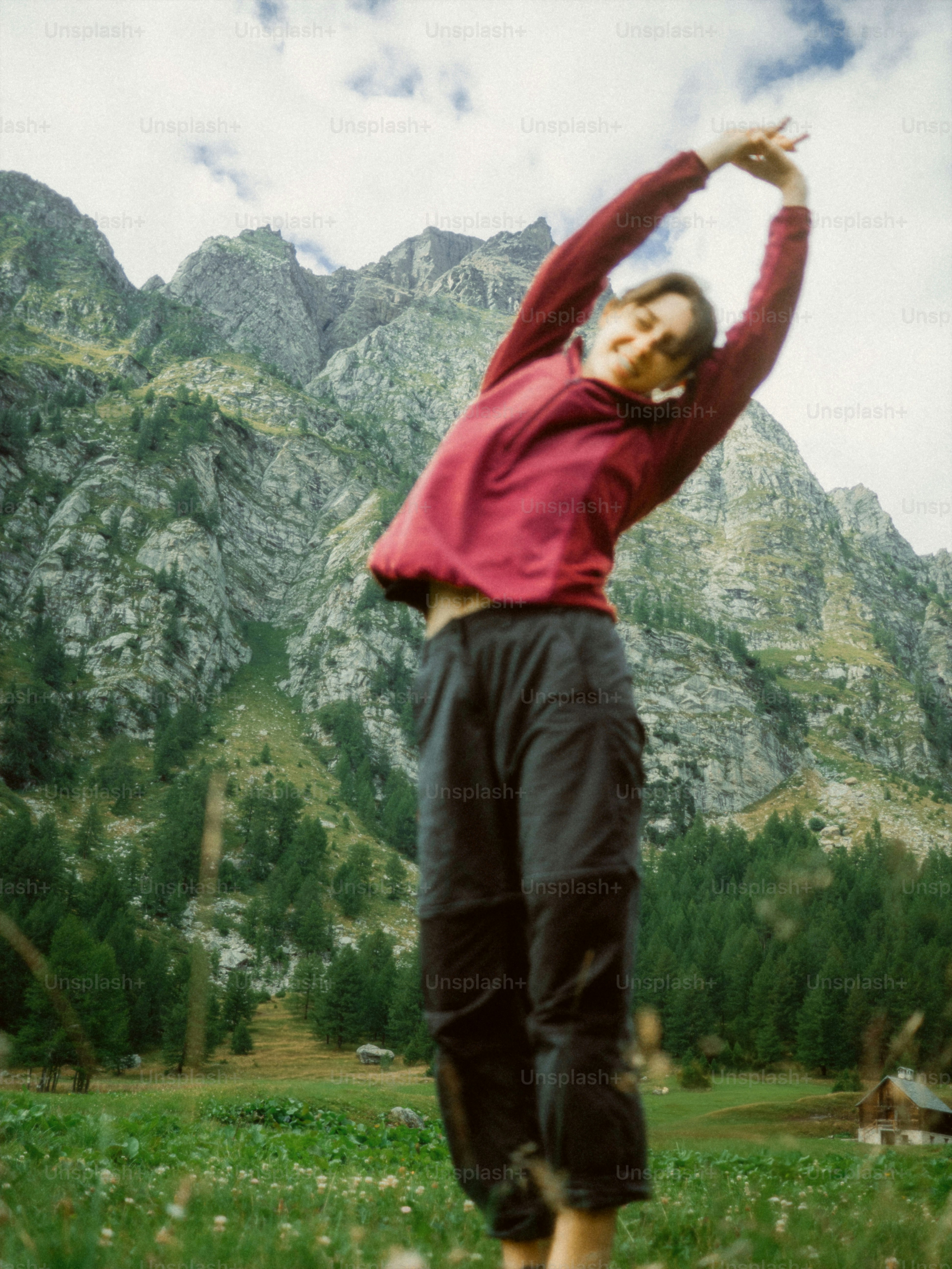 Woman stretching outdoors with mountains behind her.