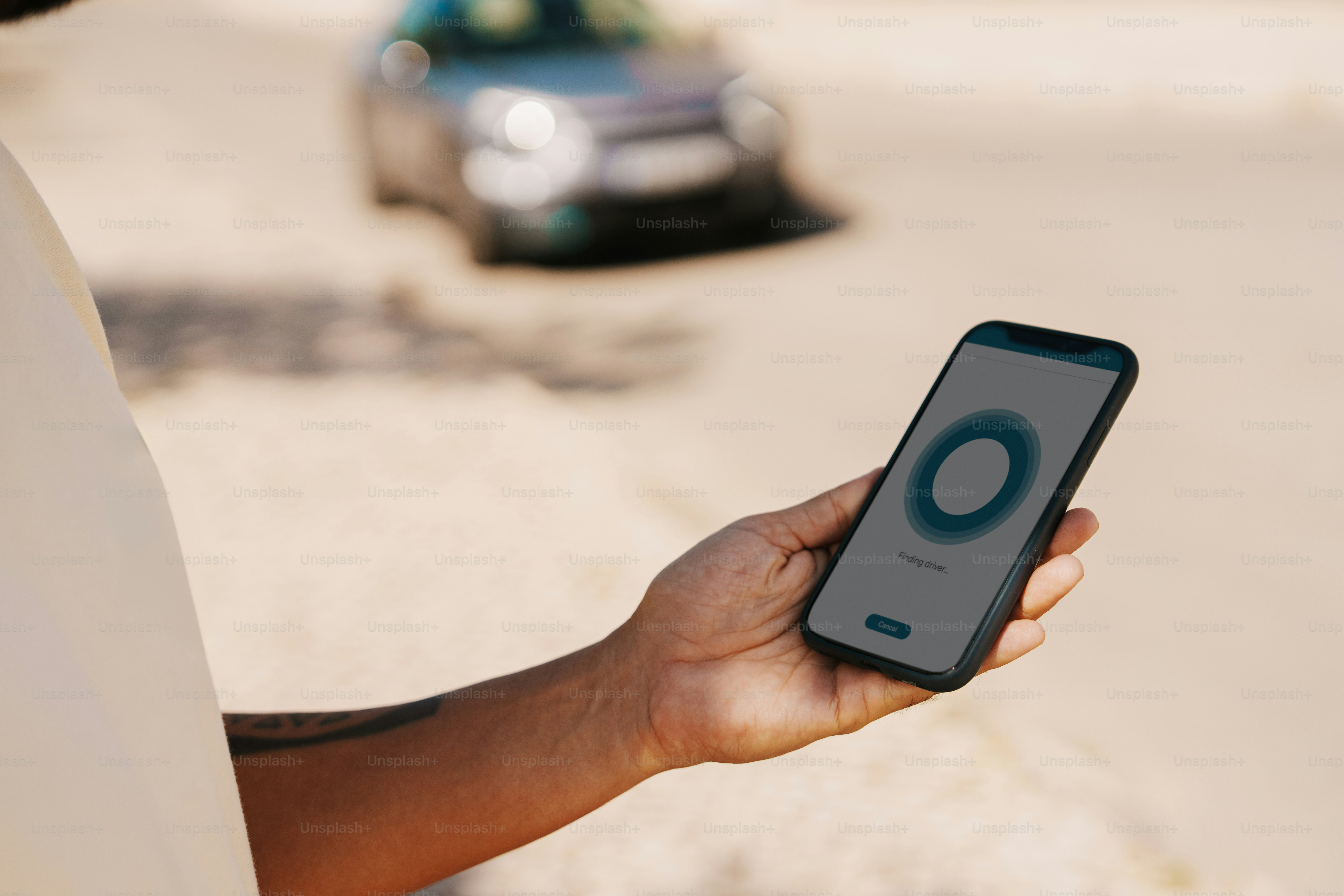 Persona usando un teléfono inteligente con el automóvil en segundo plano