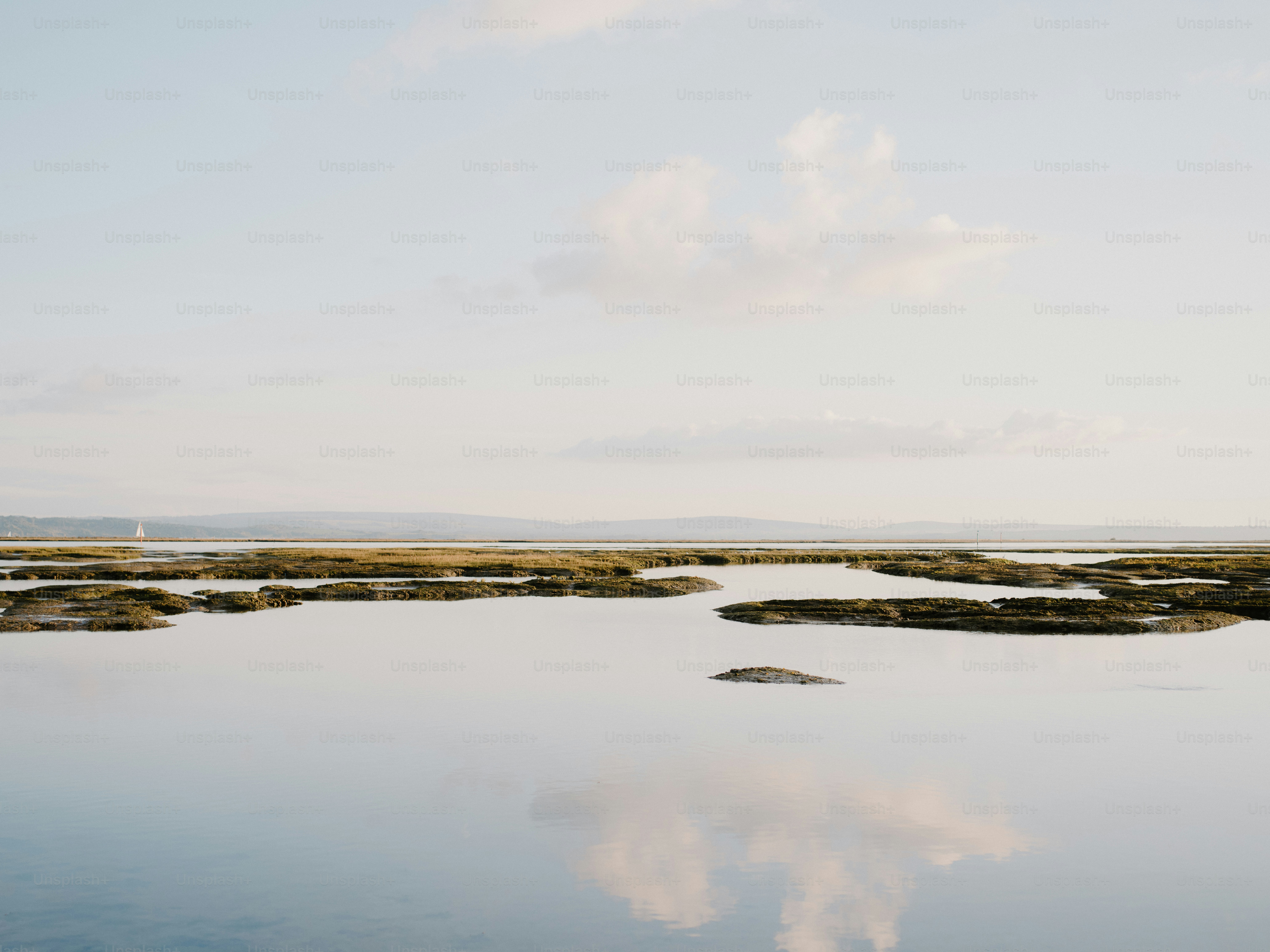 Calm water reflects the sky and distant hills. photo – Sea Image on ...