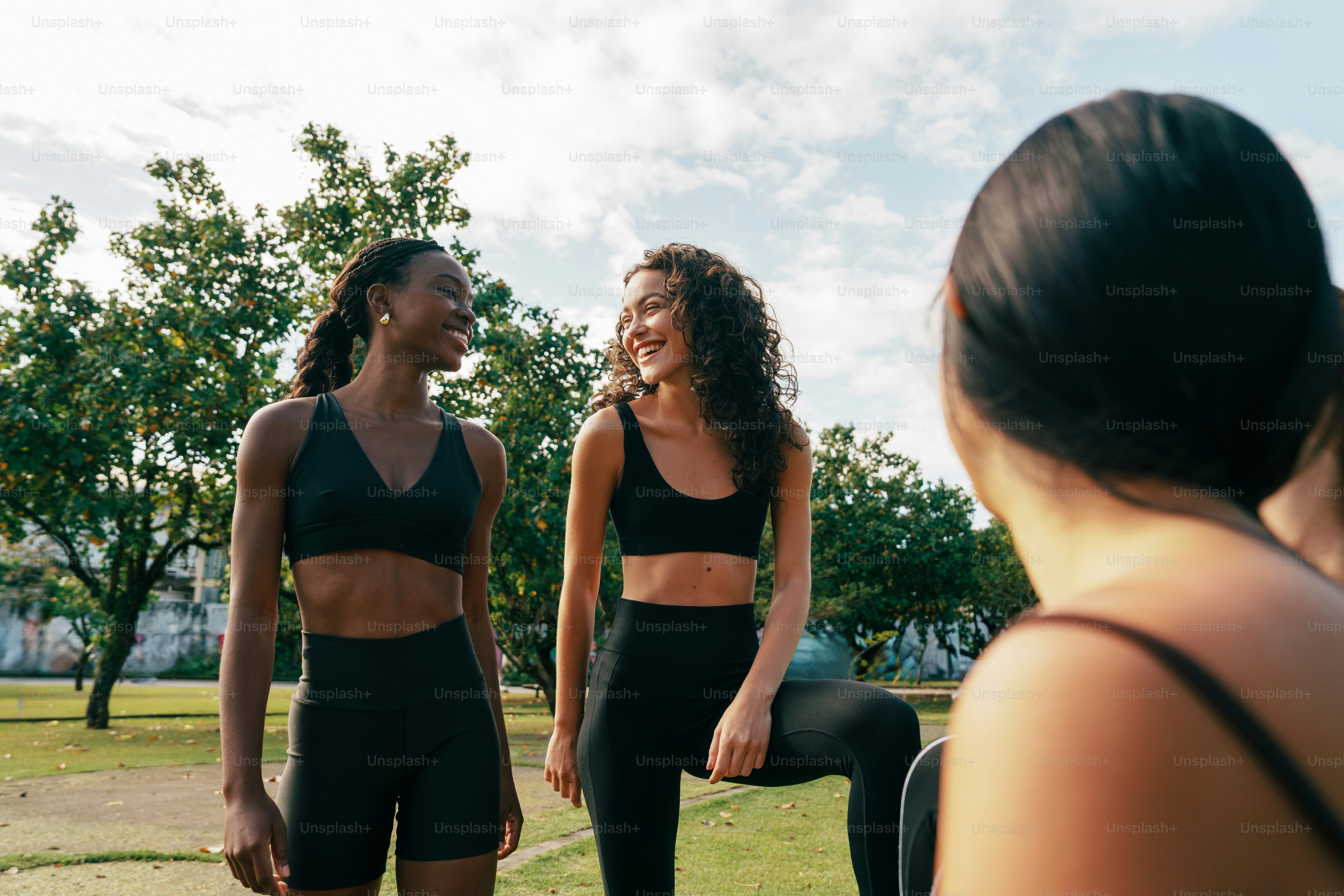 Three women in athletic wear talking outdoors.